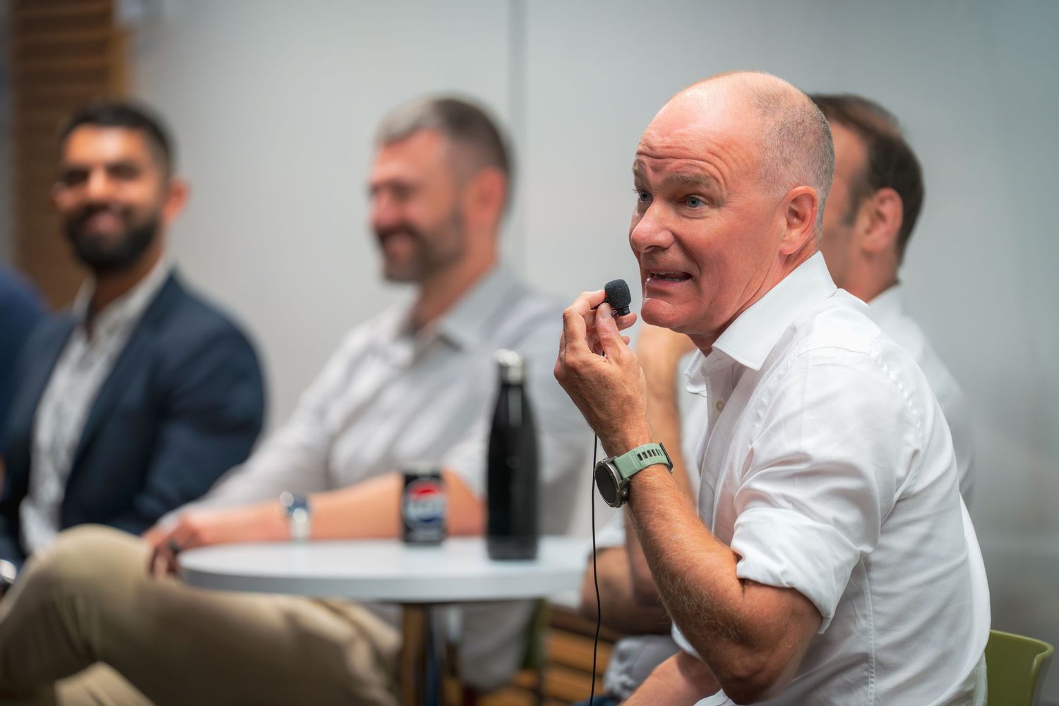Business team members participate in an animated discussion at a conference table.