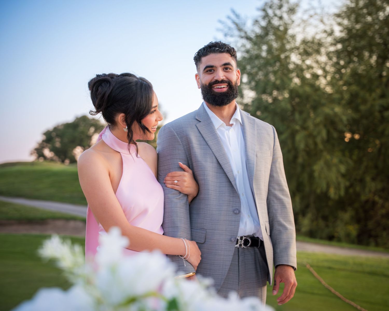 Natural light portrait session with couple on golf course with floral decorations.