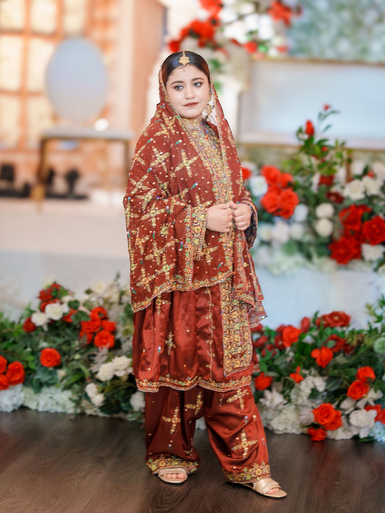 Traditional bridal footwear and dress hem details with red and white floral decorations.