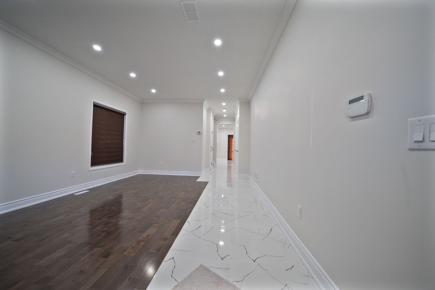 Modern interior hallway with recessed lighting, white walls, dark hardwood floors and clean contemporary design.