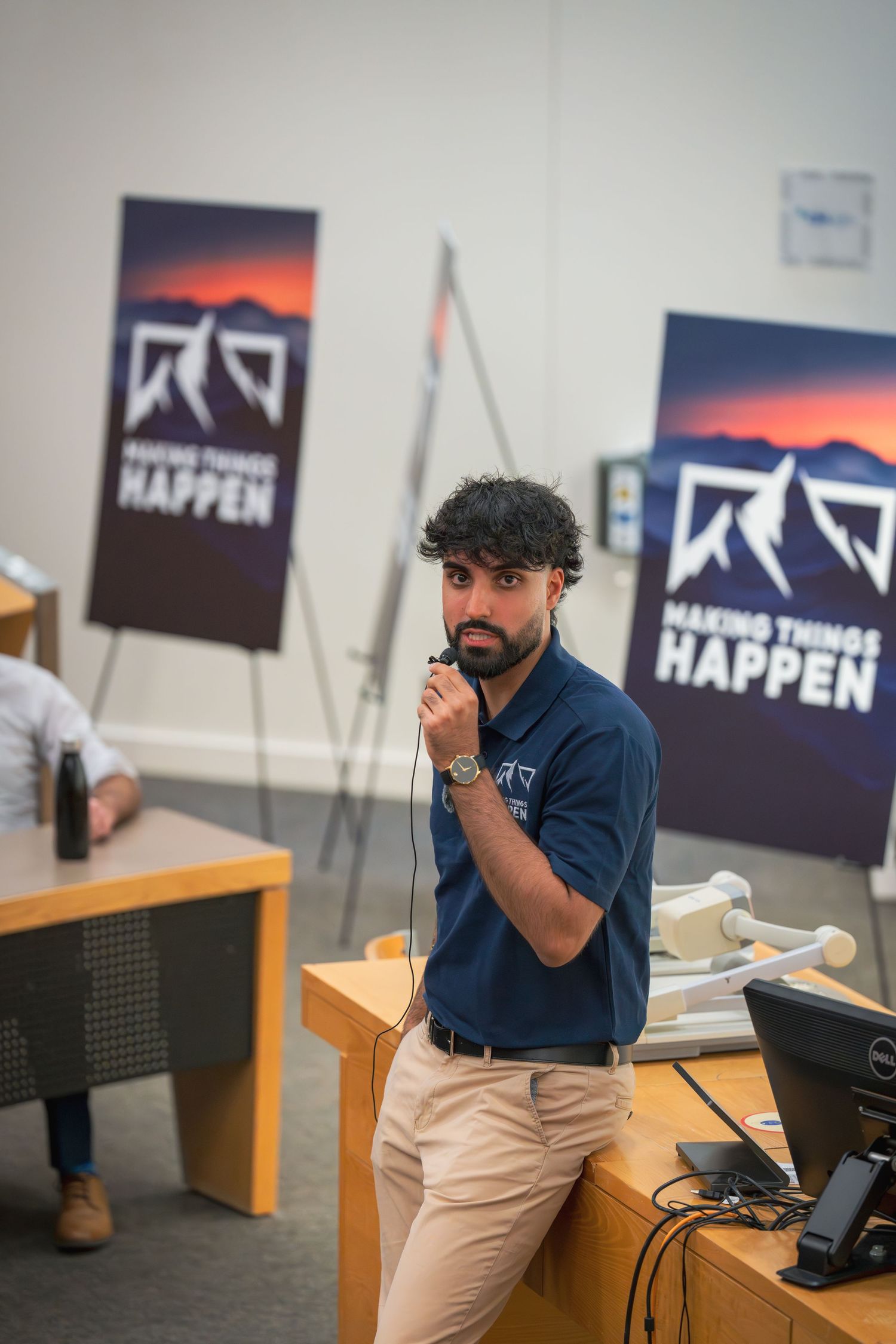 Speaker presenting in a classroom with Making Things Happen banners displayed on the walls.