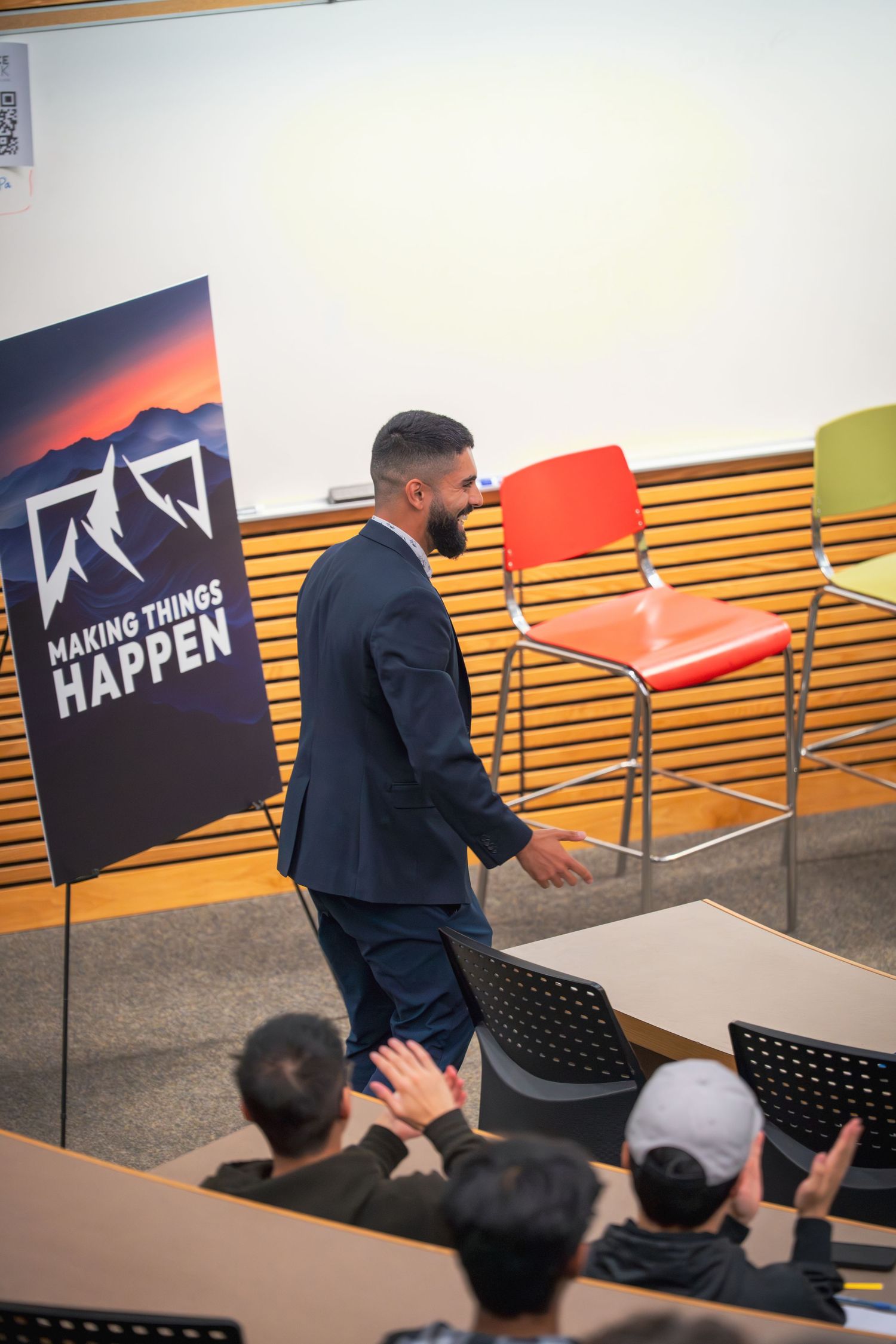 Business presentation with 'Making Things Happen' banner displayed in a lecture hall setting.