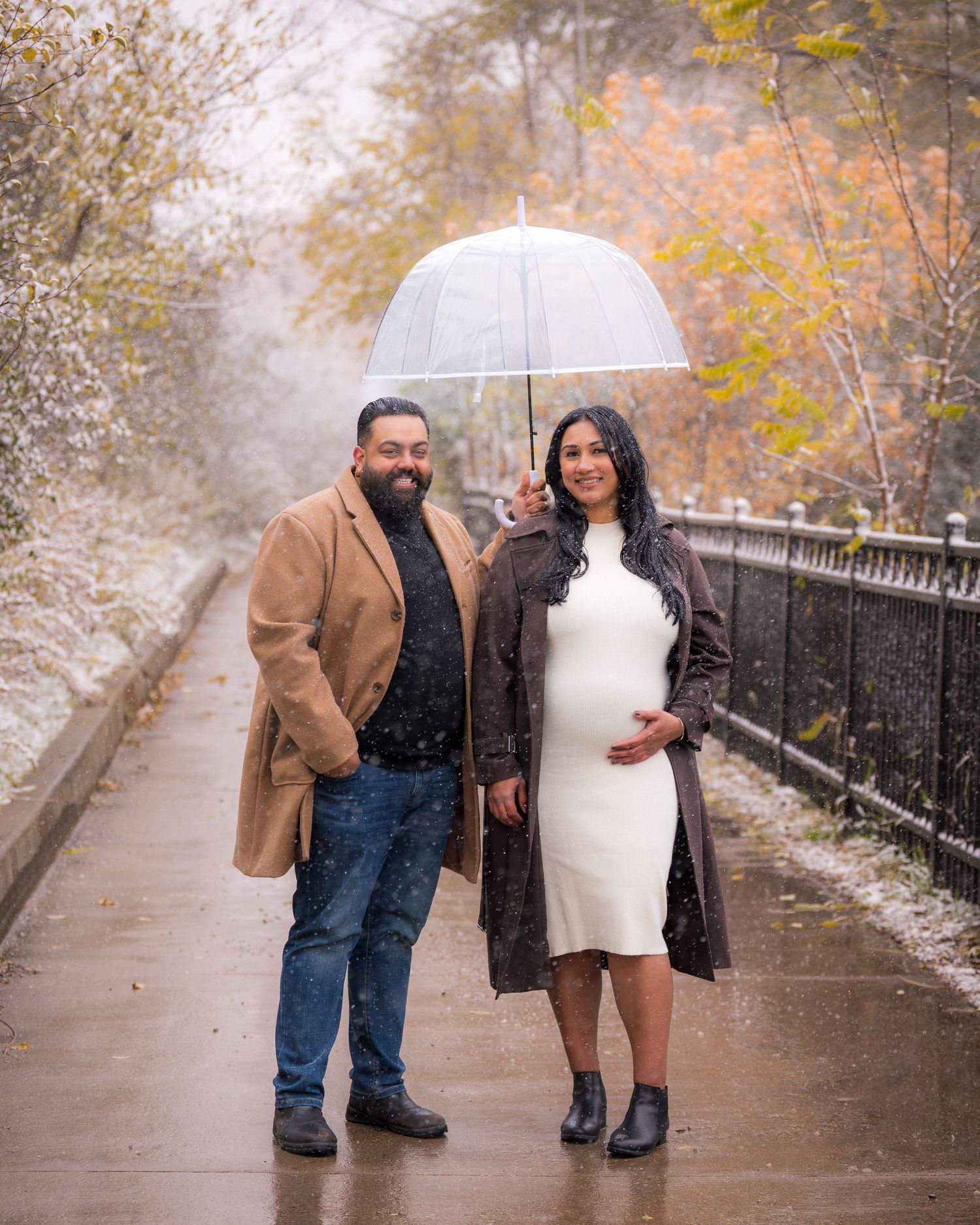 Couple walking together under an umbrella on a snowy autumn day.