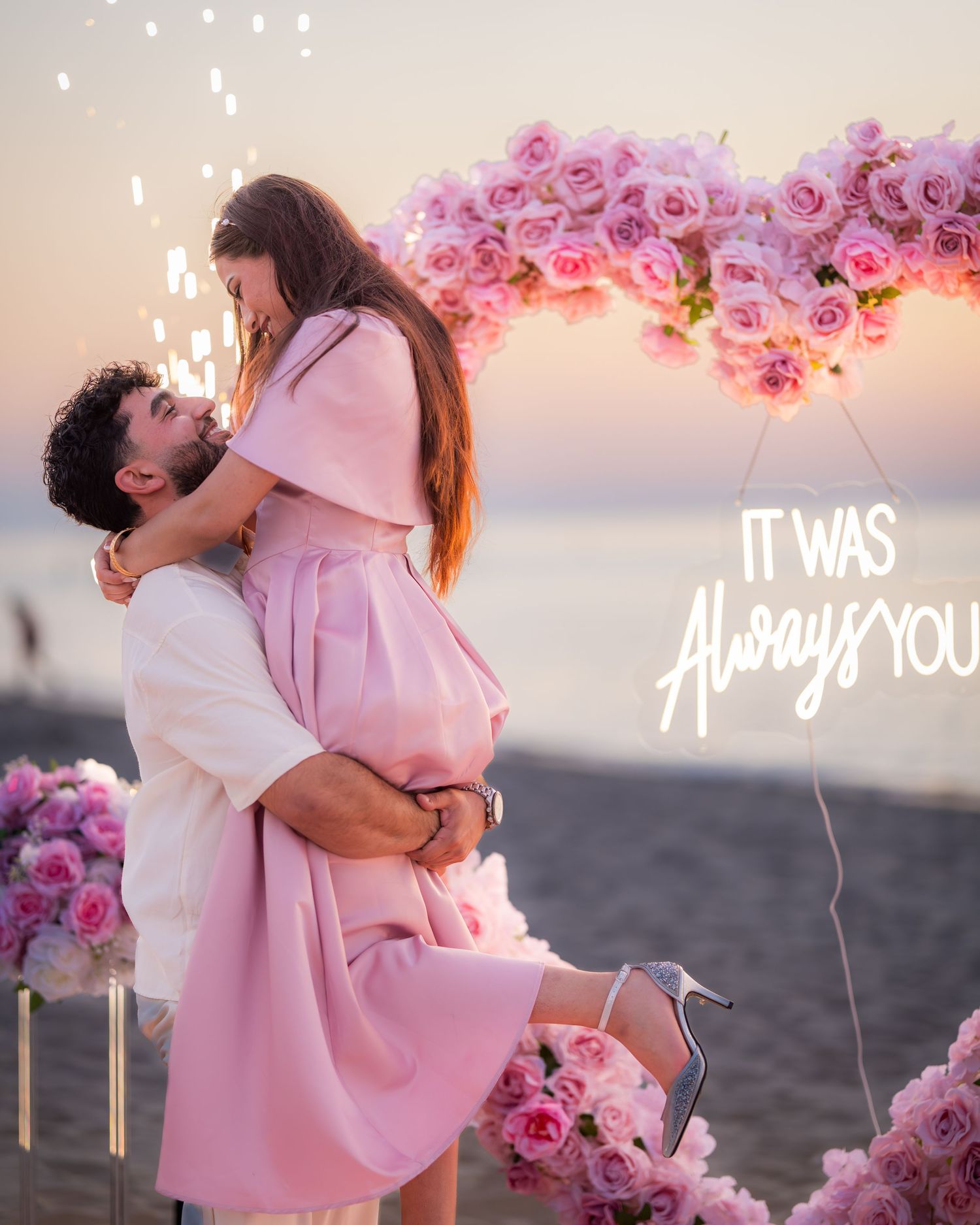 Romantic sunset proposal scene with pink roses and glowing text 'It Was Always You' against beach backdrop.