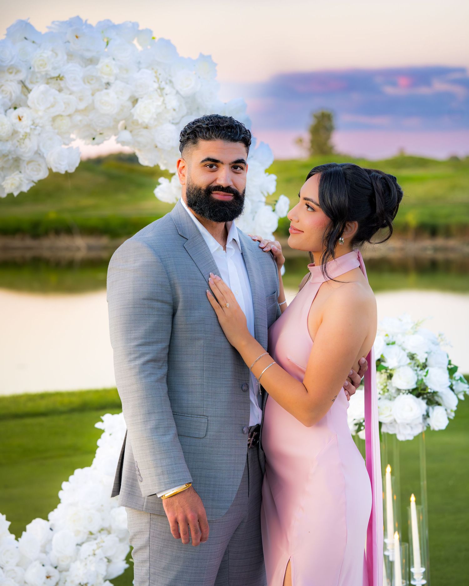 A couple shares a tender moment during their sunset photo session under white flowers.