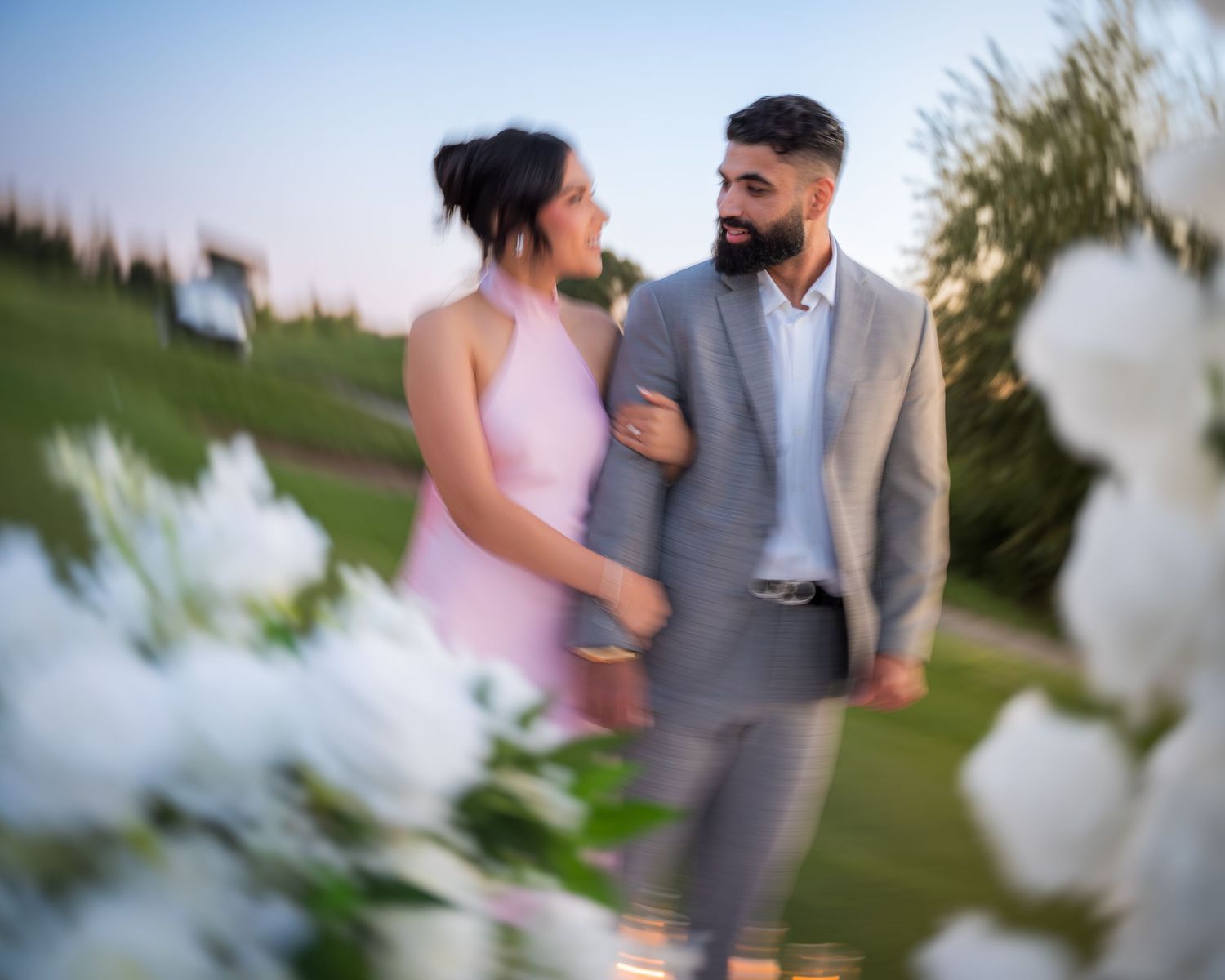 Couple in pink and grey attire share an intimate moment outdoors.