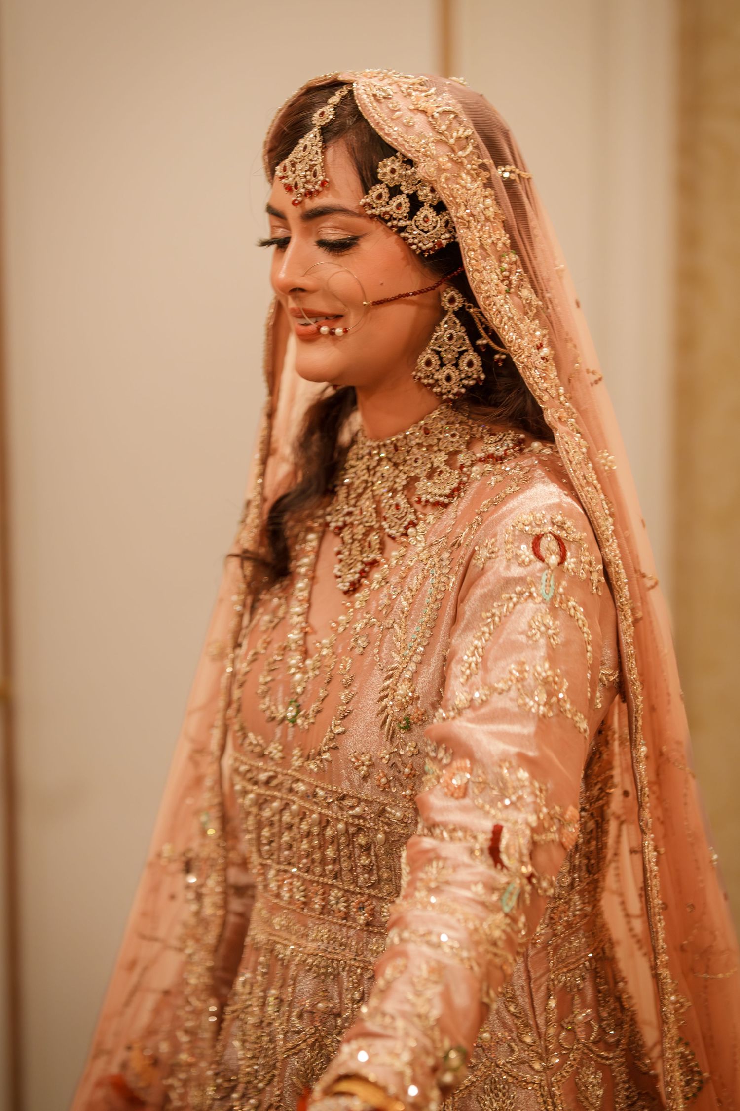 Close-up details of a peach bridal lehenga with intricate gold embroidery and embellishments.