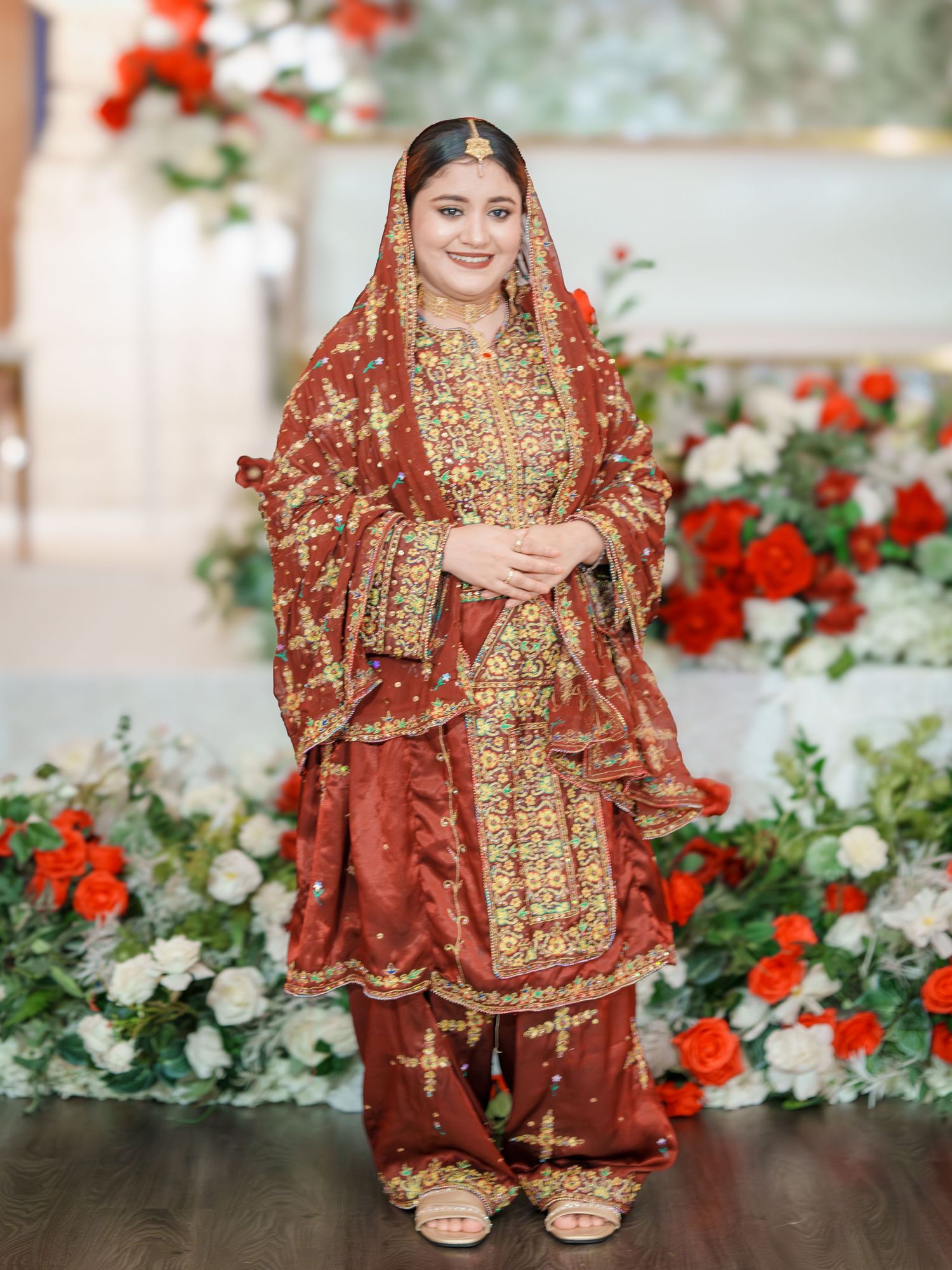 Bridal portrait session showcasing traditional South Asian wedding attire against floral backdrop.