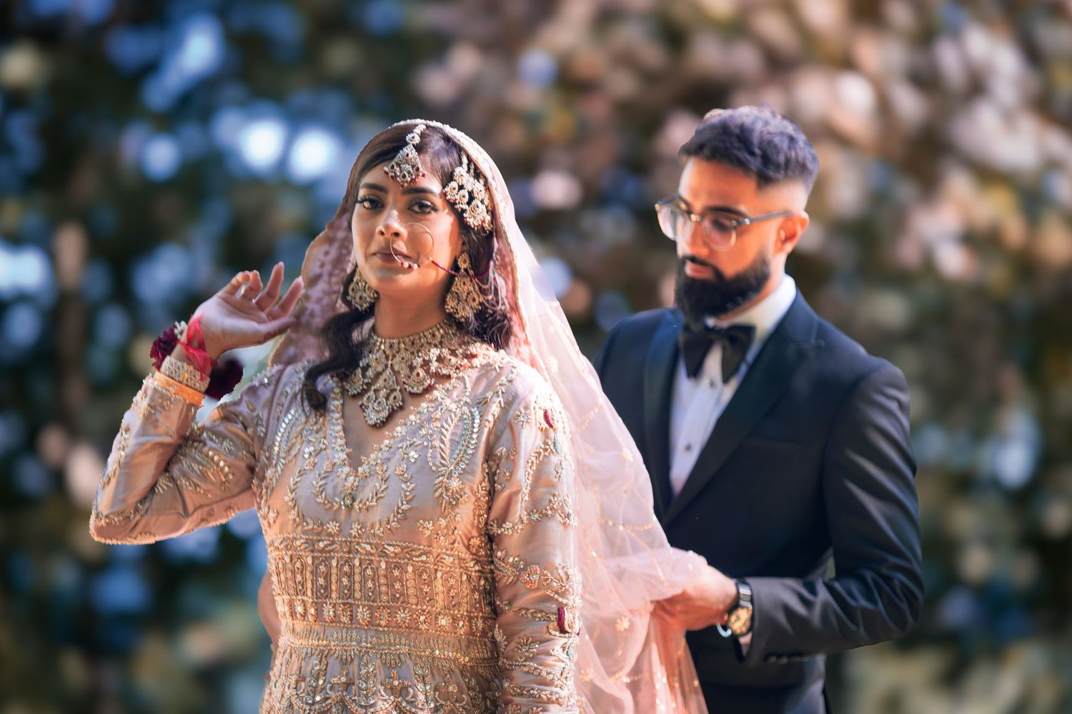 Couple shares intimate moment in outdoor wedding photoshoot with natural lighting.