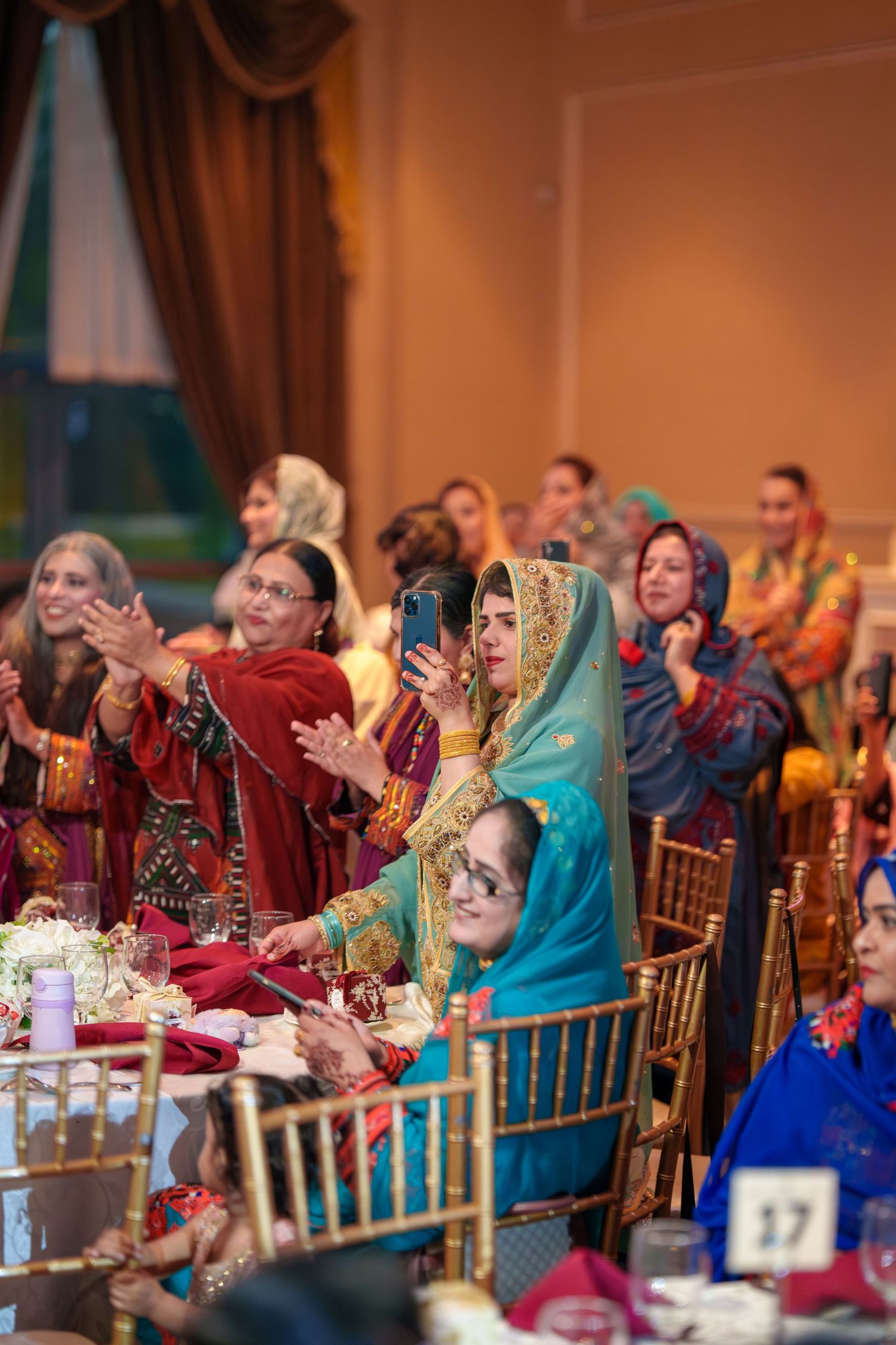 Wedding reception guests in colorful traditional attire seated at decorated tables.