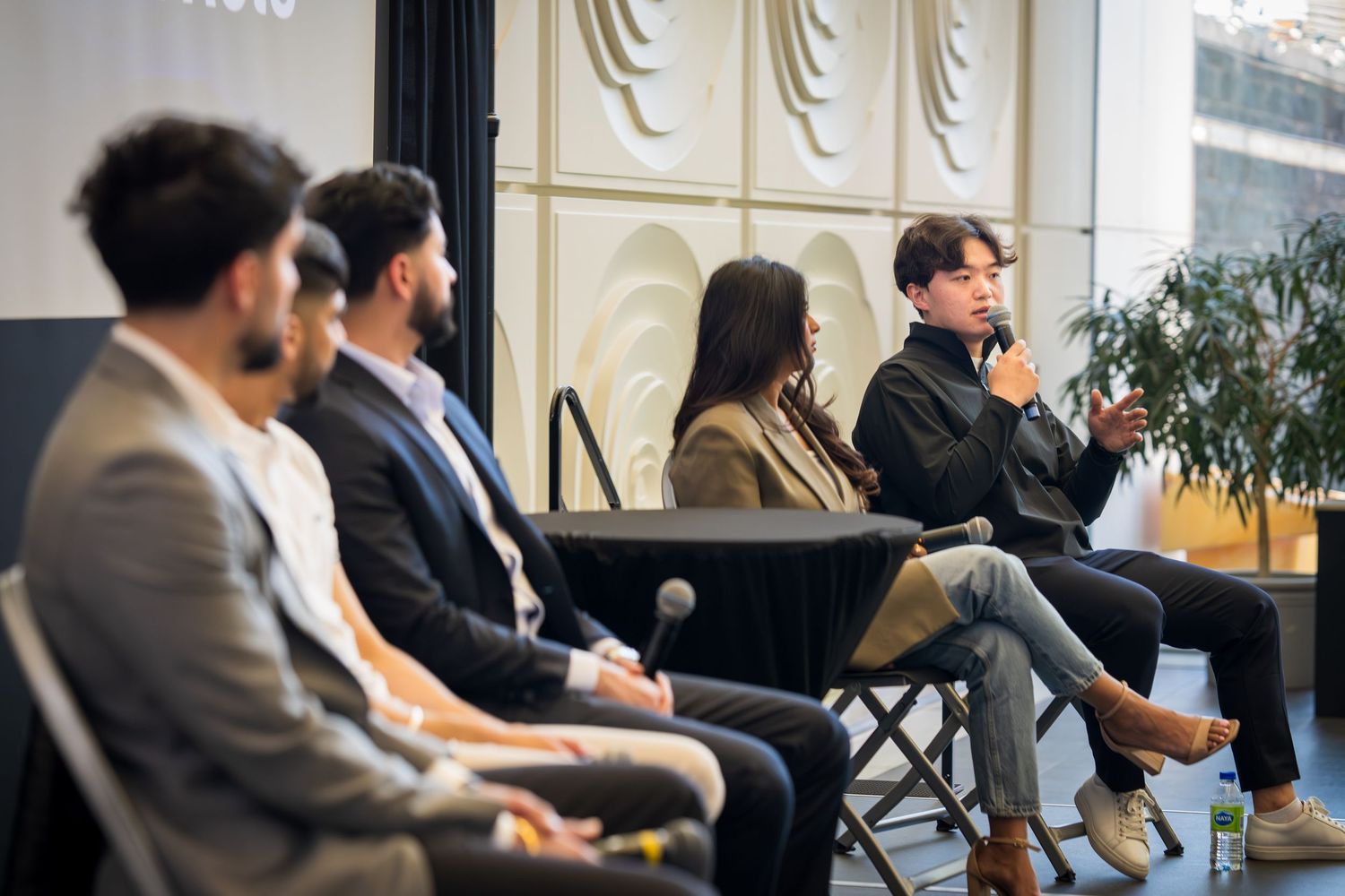 Side view of professional panel discussion with multiple speakers seated on stage.