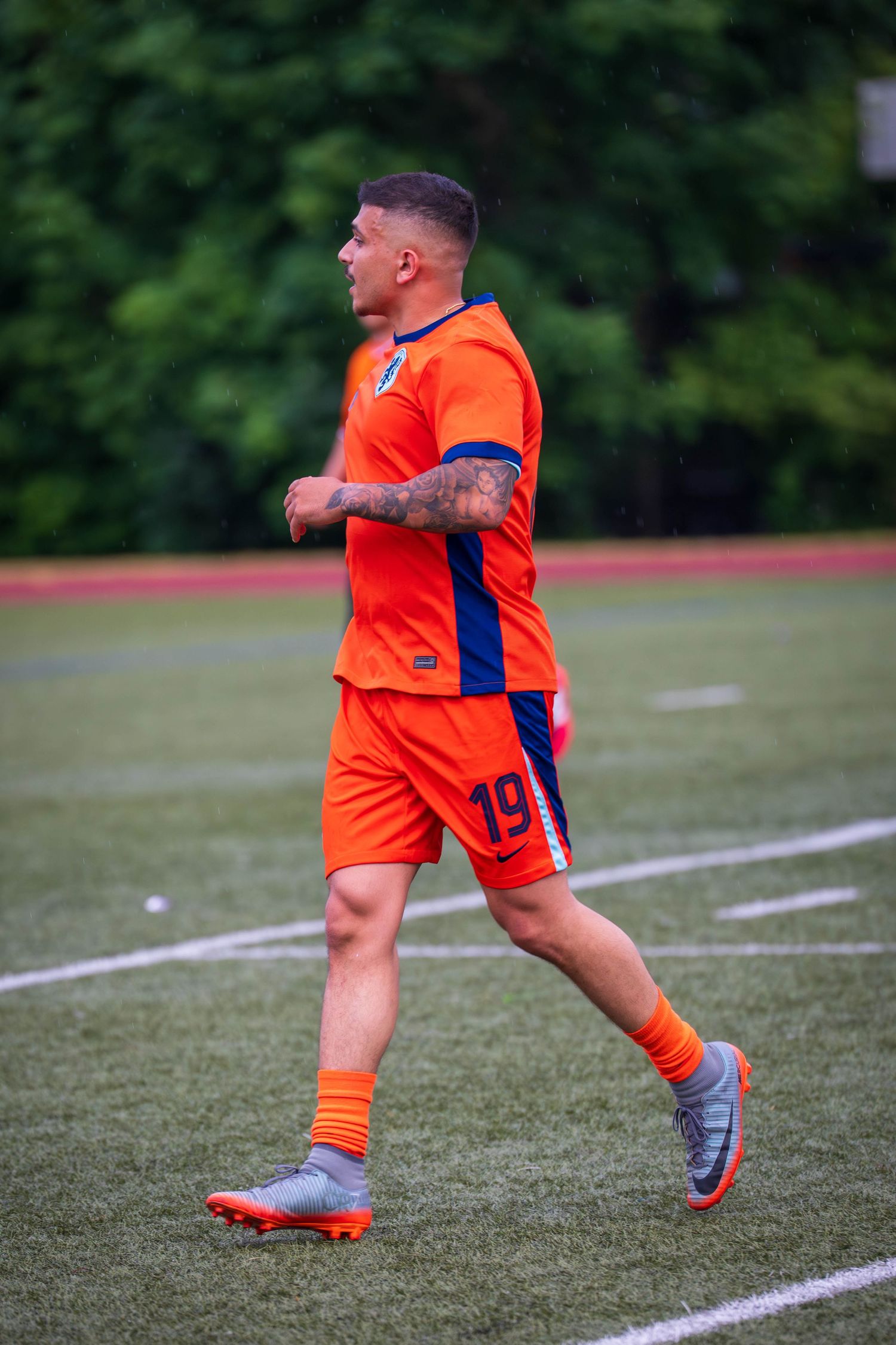 Player in orange uniform practicing soccer moves along white sideline.
