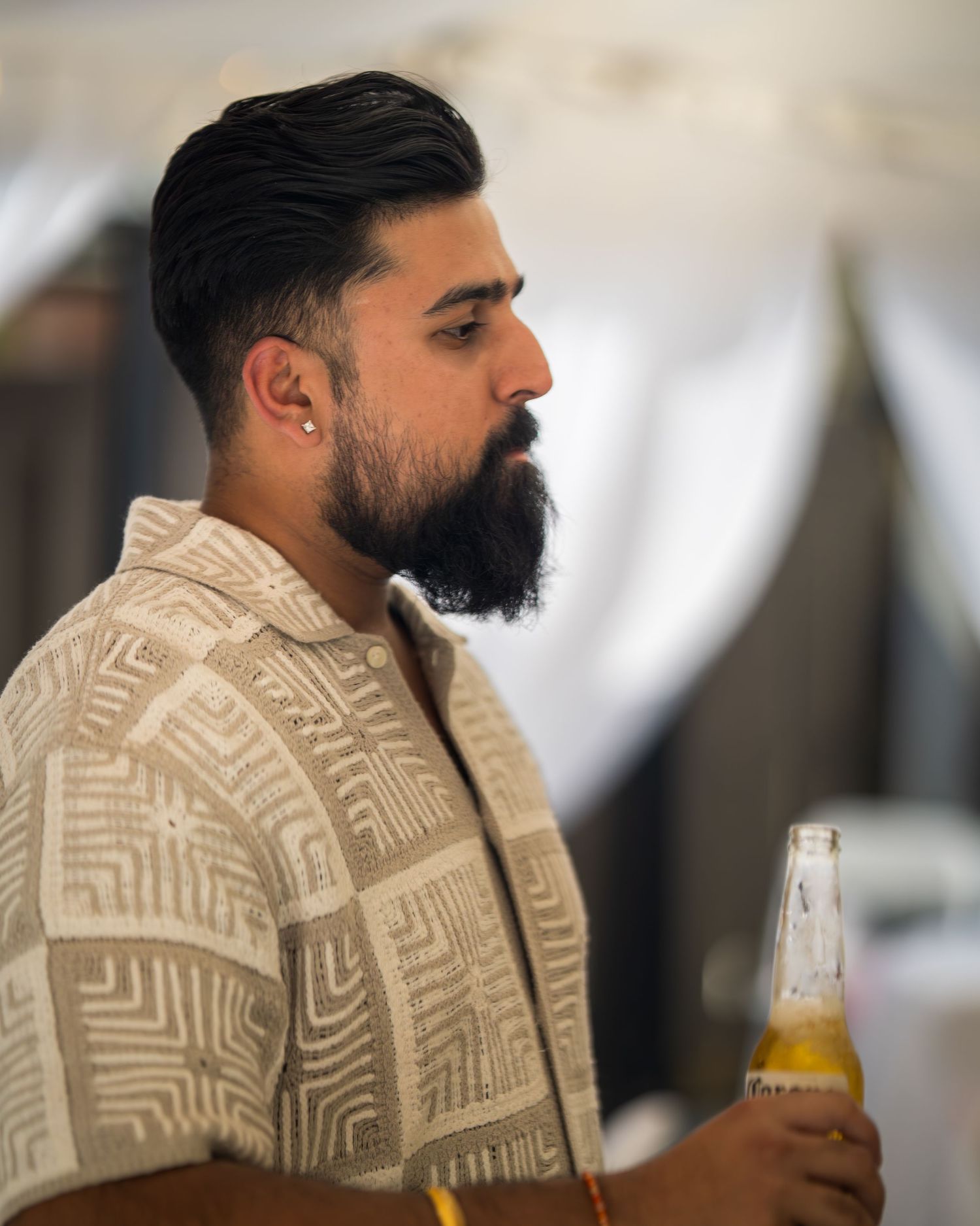 Guest in geometric print shirt drinking from a bottle at a celebration.