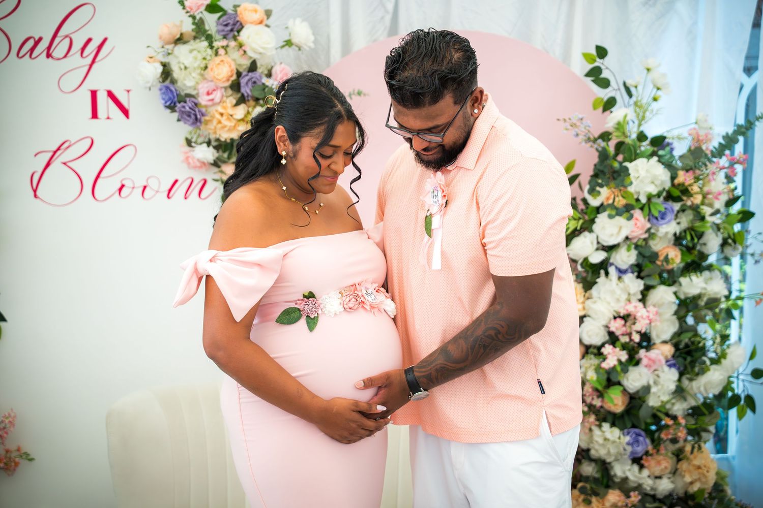 Couple embracing at baby shower event with elegant floral arrangements.