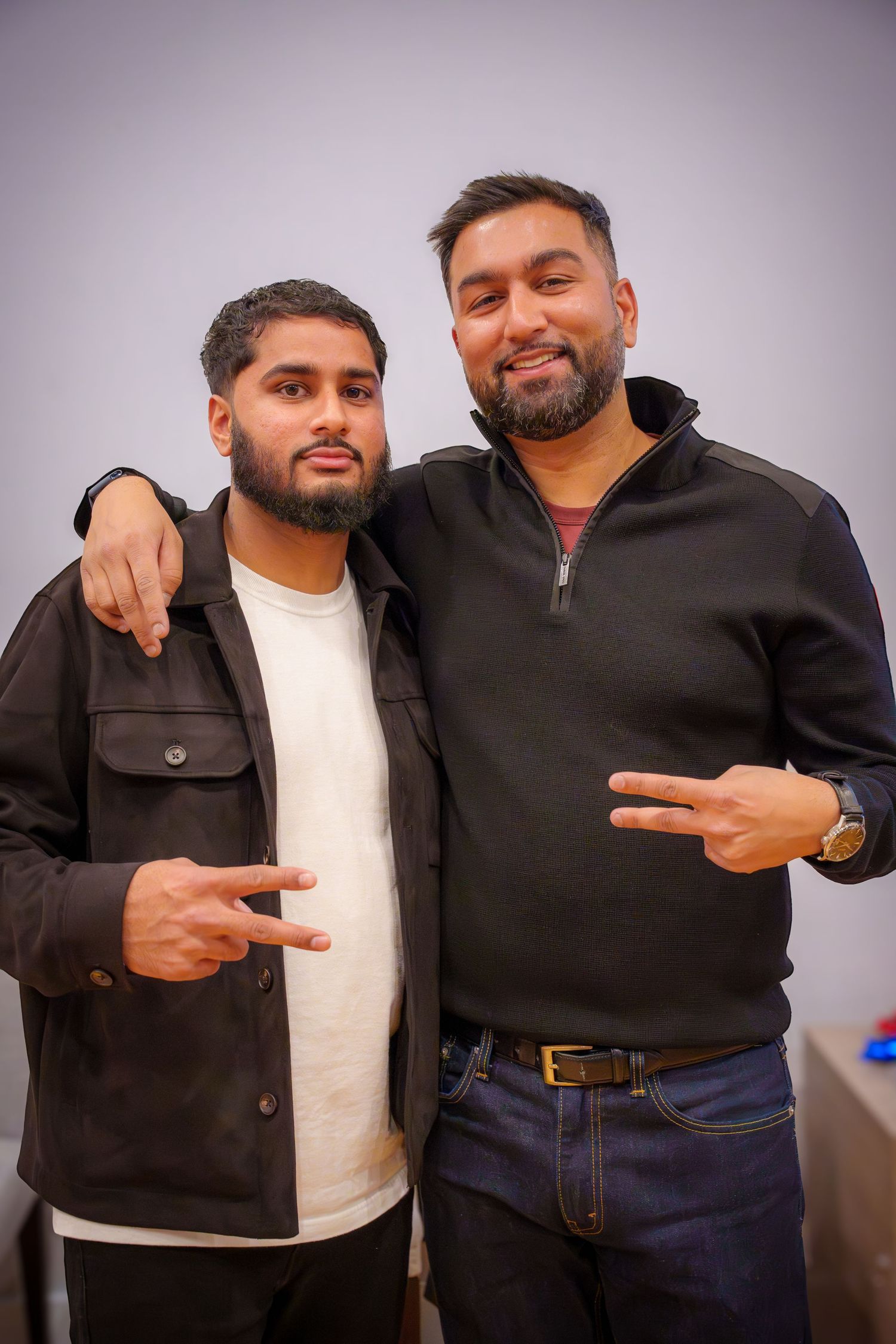 Friends in casual attire posing together against a grey background.
