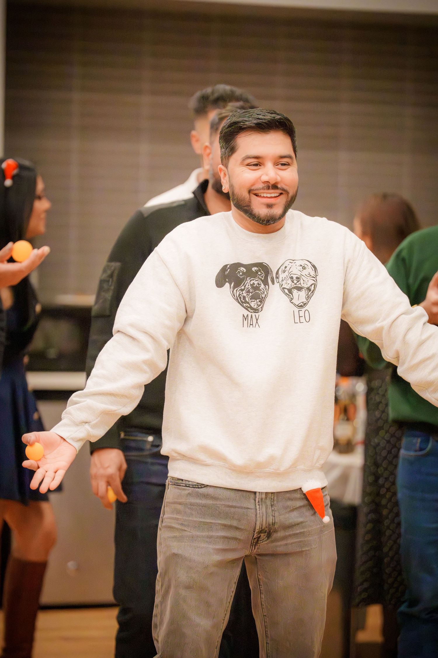 Person wearing a white sweater with graphic design spreads arms wide in an animated gesture.