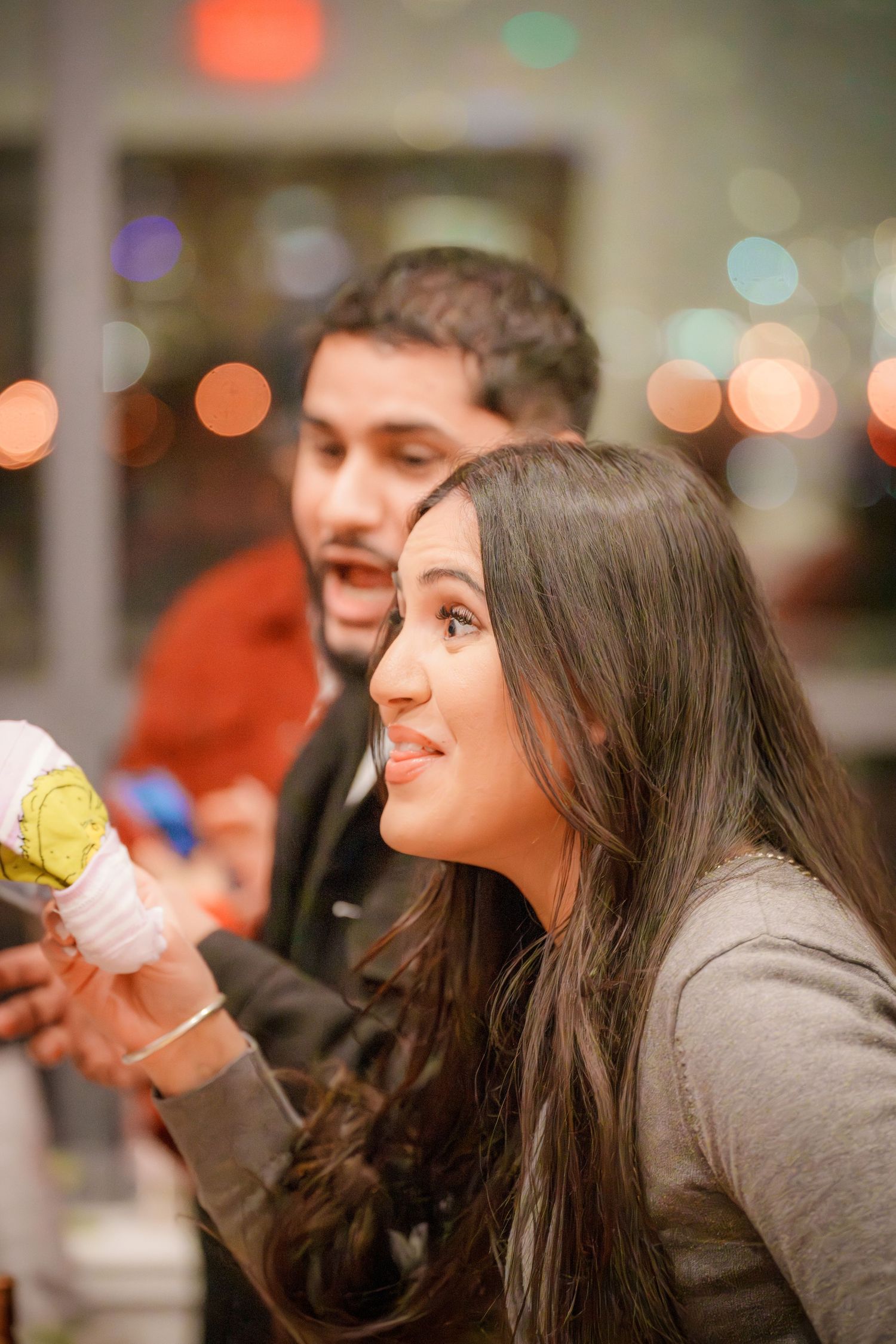 People laughing and socializing at a gathering with warm ambient lighting.
