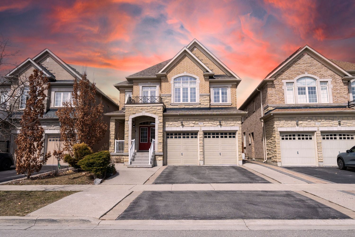 Modern suburban house with beige exterior and double garage under dramatic orange and pink sunset sky.