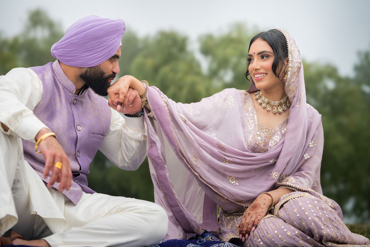 Couple in matching lavender outfits share intimate moments during their outdoor wedding photoshoot.