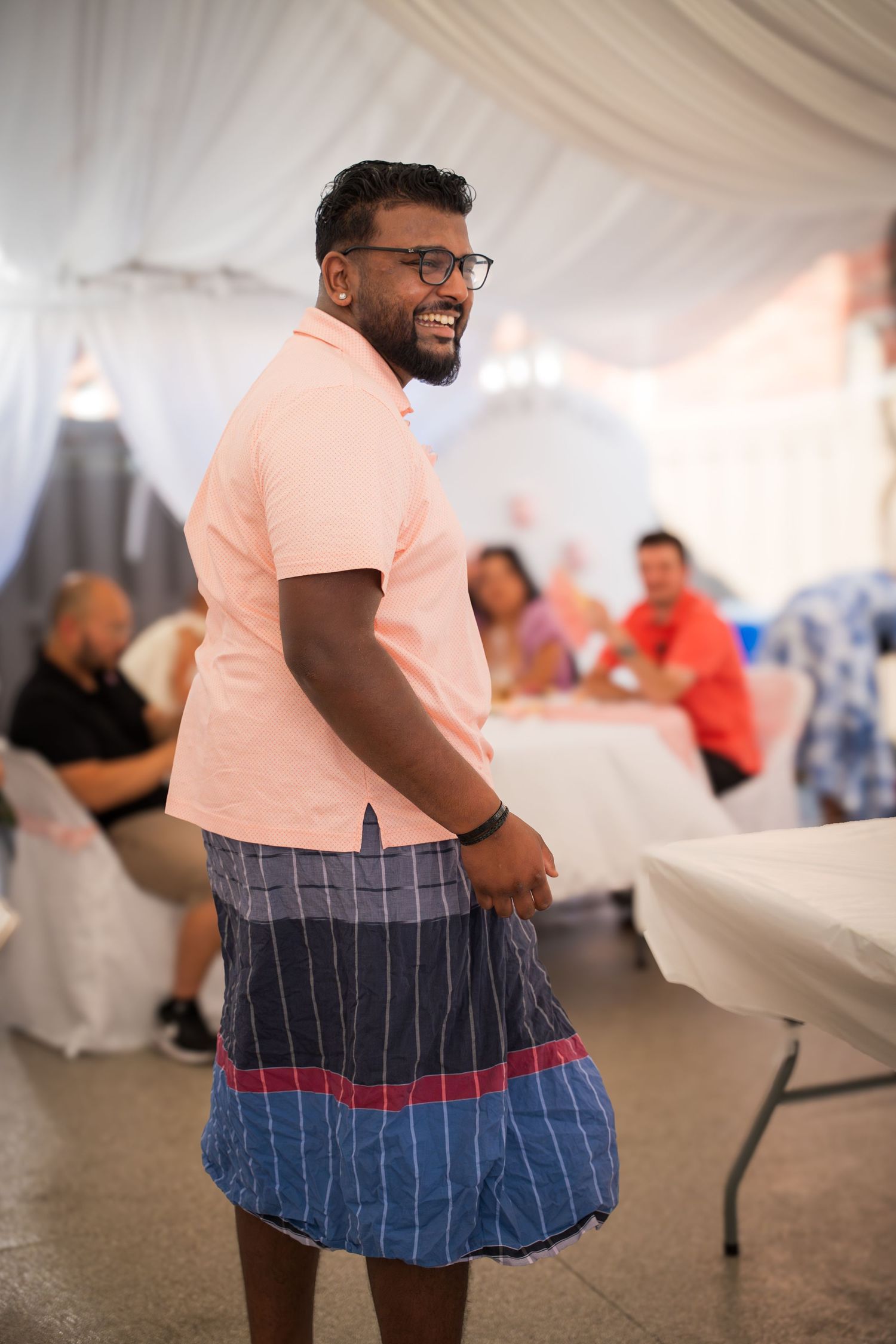 Guest in a peach shirt and patterned shorts enjoying themselves at an indoor party.