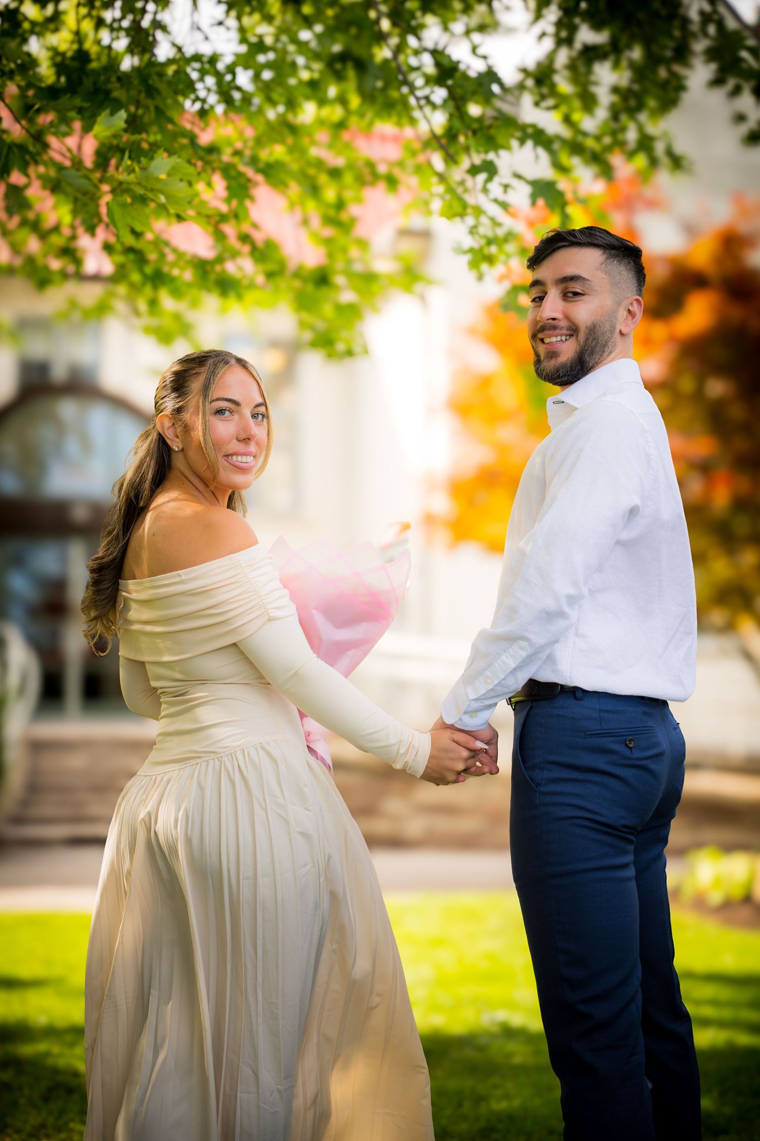 A couple dancing in a garden with golden sunlight filtering through autumn trees.