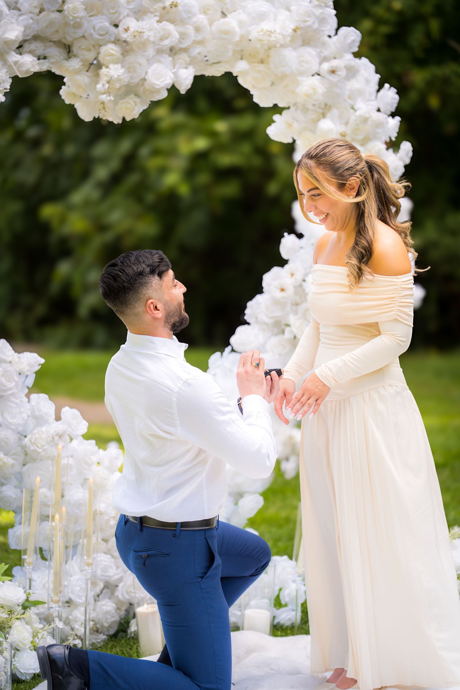 A joyful wedding dance captured beneath an ornate white floral arch in a garden setting.