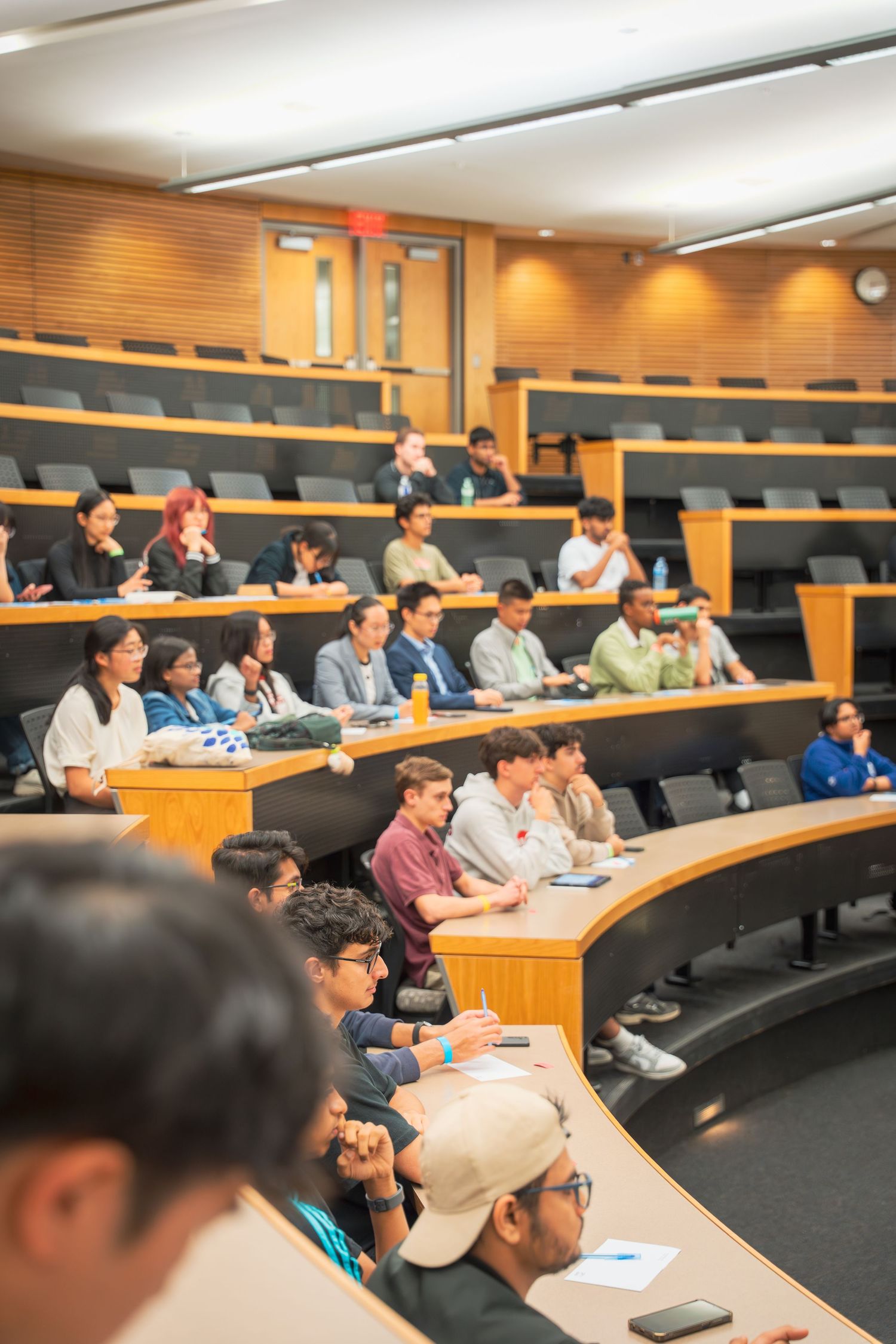 Students seated in tiered lecture hall rows attending a business presentation.