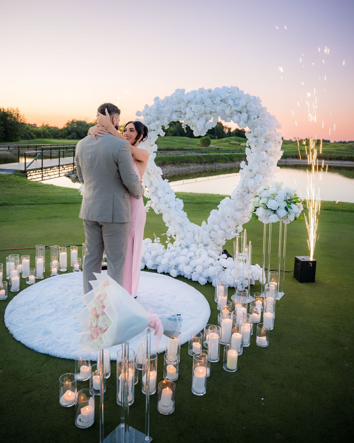 Romantic proposal scene with sparkling lights and floral decorations at twilight.