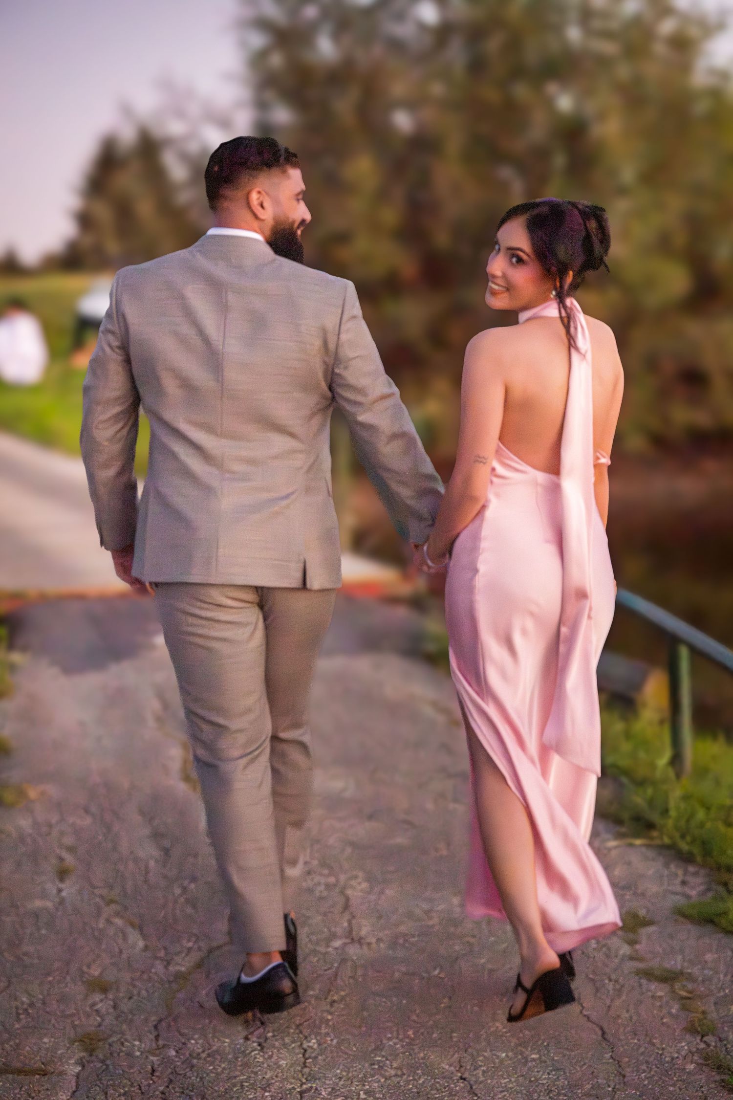 Couple taking romantic walk on gravel path in evening light.
