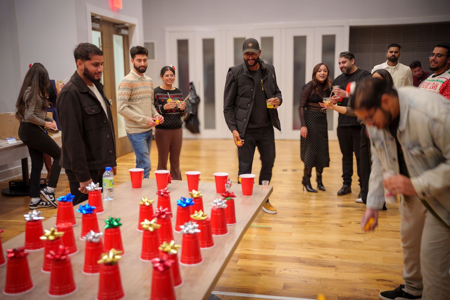 Red party cups arranged in rows on wooden floor for indoor game setup.