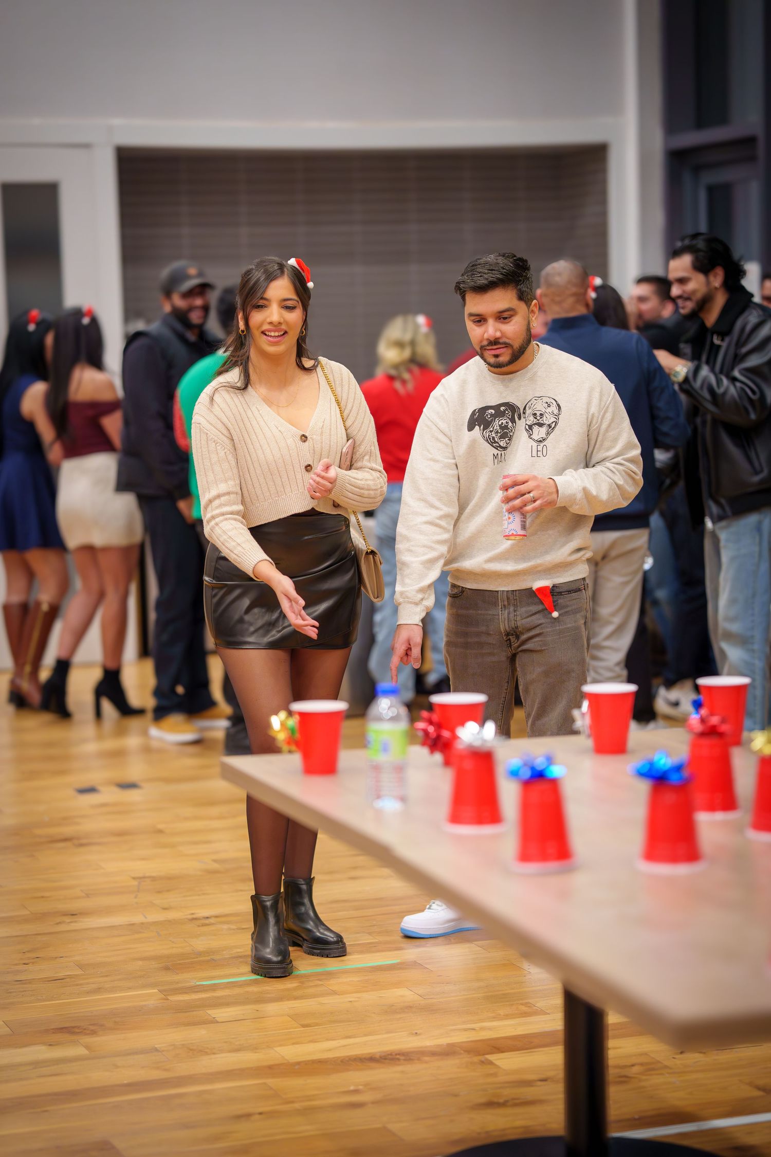 Players engaged in competitive cup game on wooden floor at indoor event.