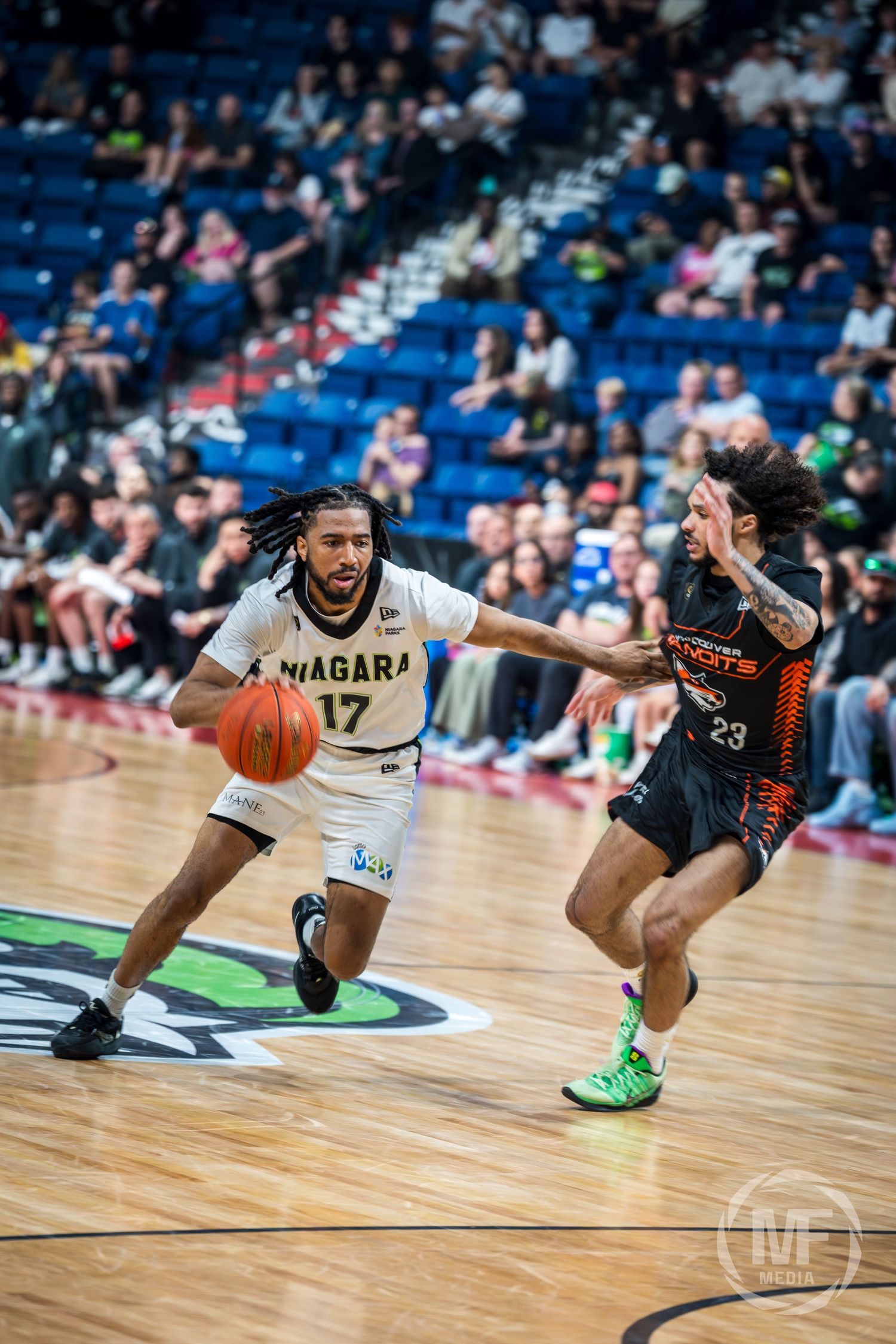 Niagara basketball player dribbling past defender during a professional indoor arena game.