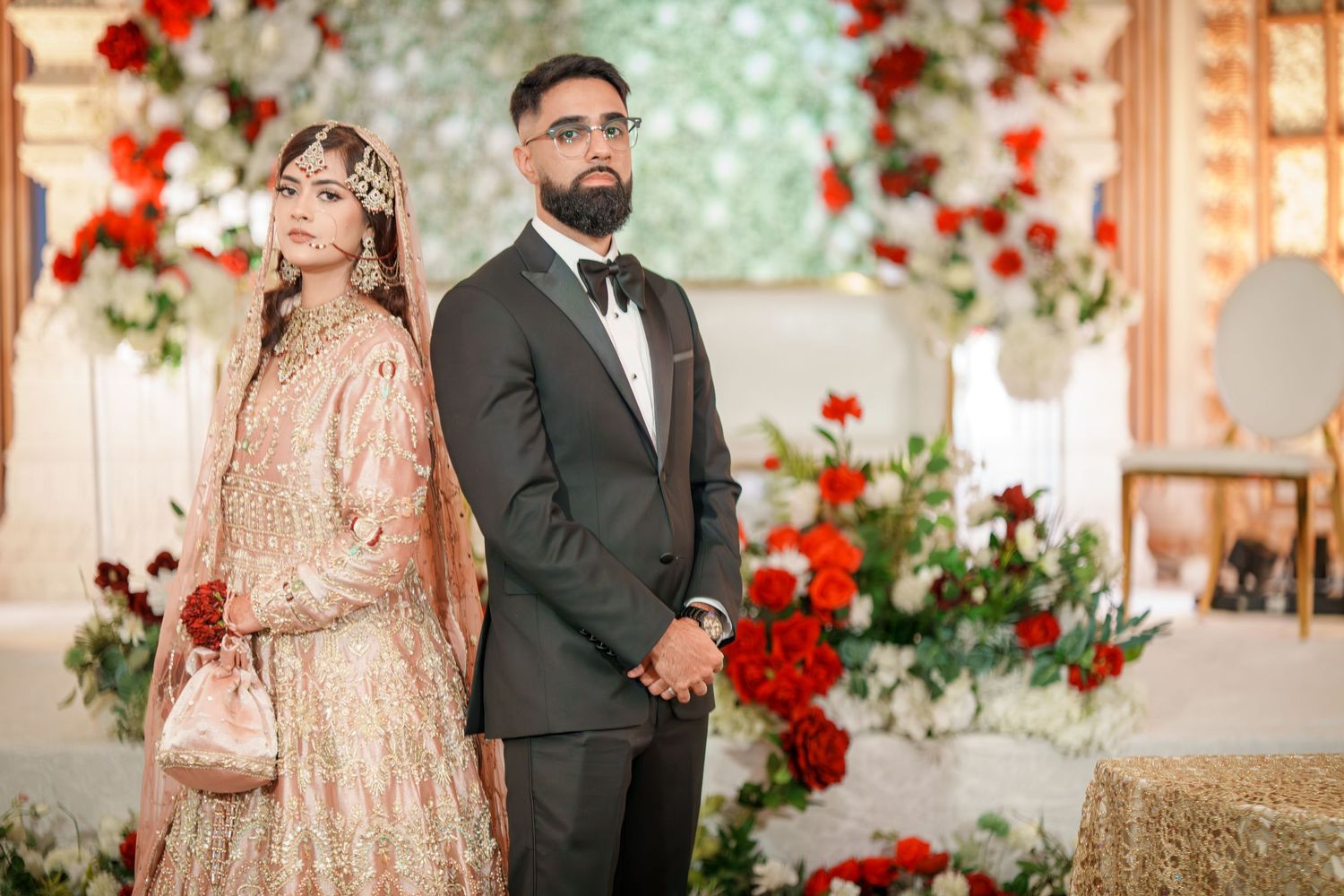 Wedding ceremony setup with red rose floral arrangements and elegant decor against a soft green backdrop.