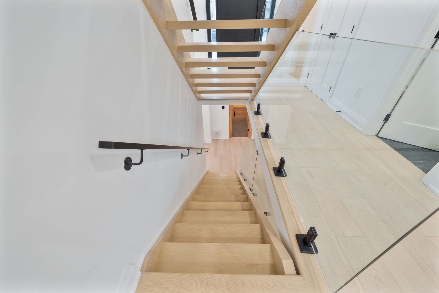 Modern staircase with glass railings and light wood treads in a minimalist interior design.