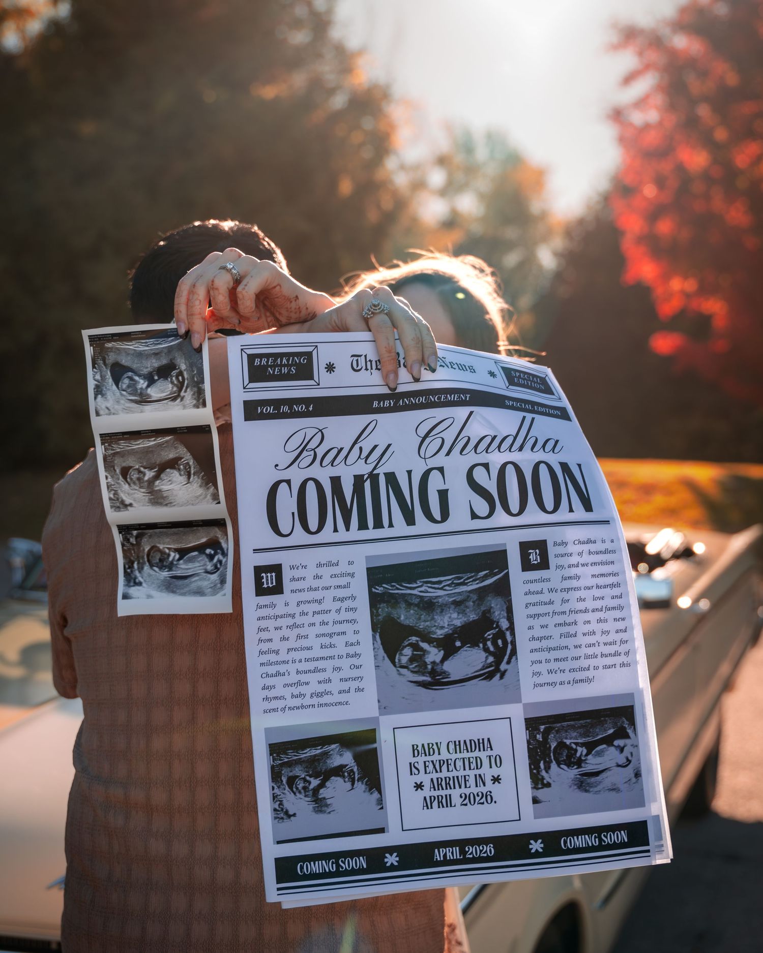 A series of ultrasound pregnancy announcement photos being held up against a sunset-lit background.