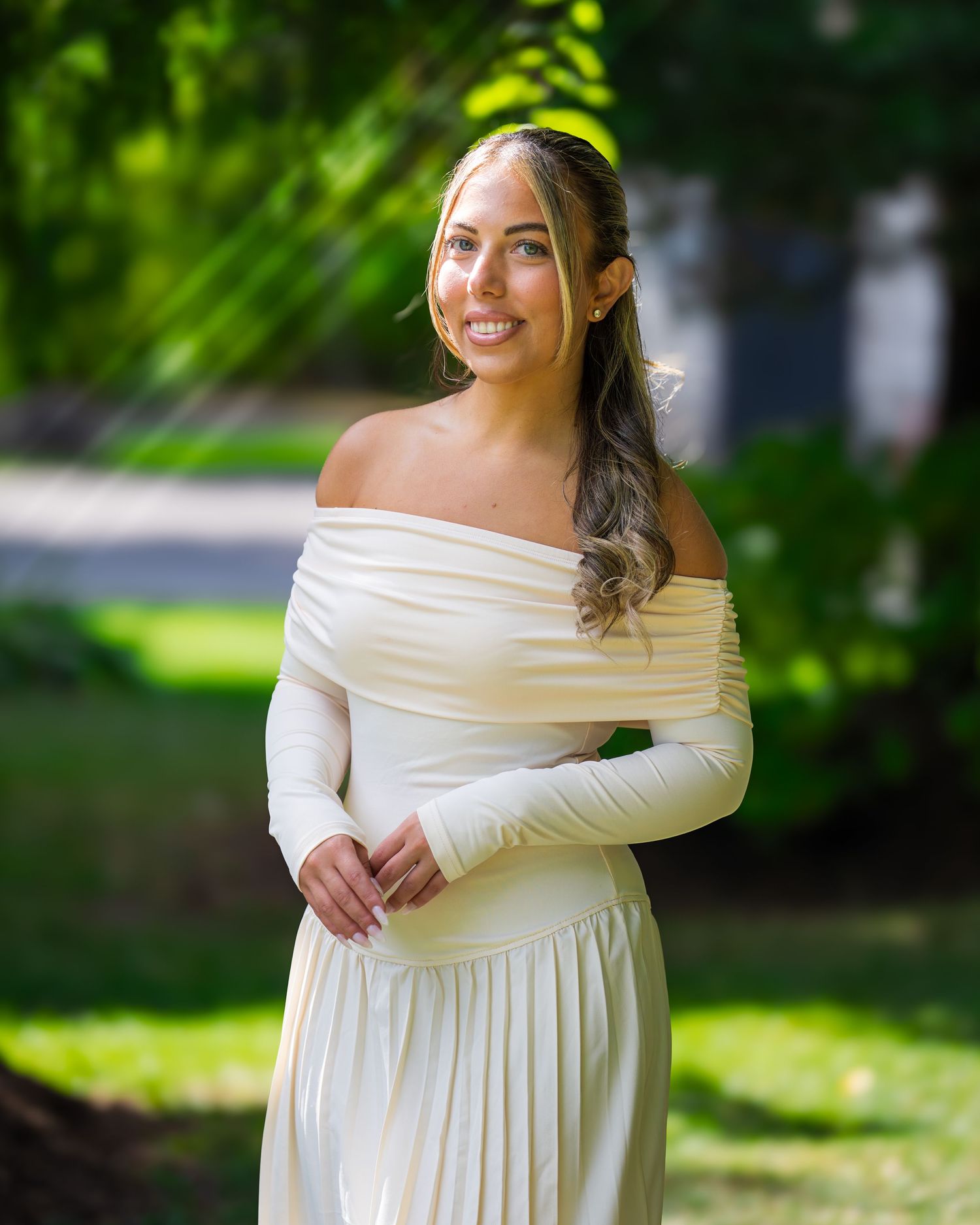 Elegant bridal portraits in off-shoulder white dress against green foliage.