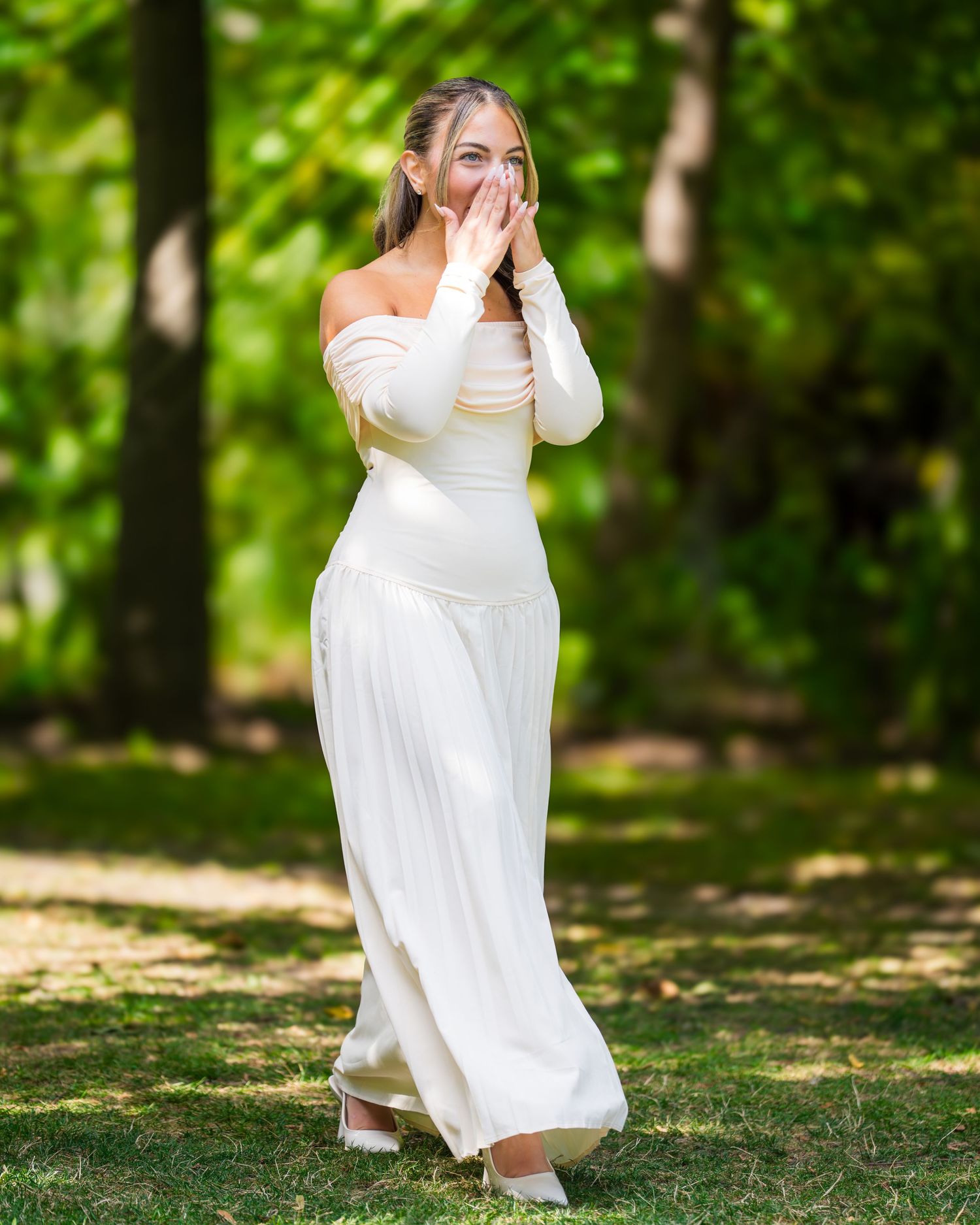A bride in a flowing white dress dancing in a sun-dappled forest clearing.