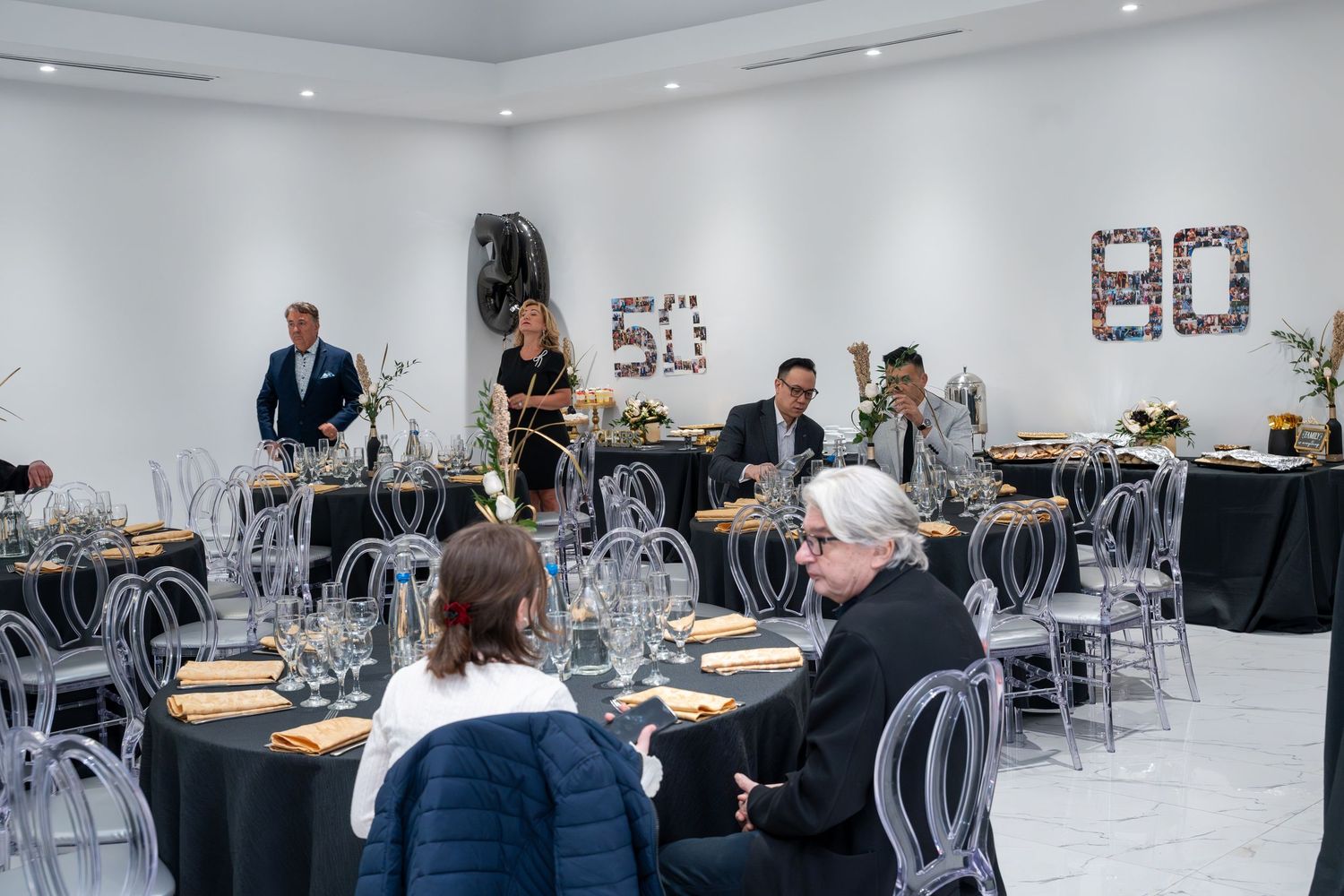 Modern event space with clear chairs and tables set up for celebration.