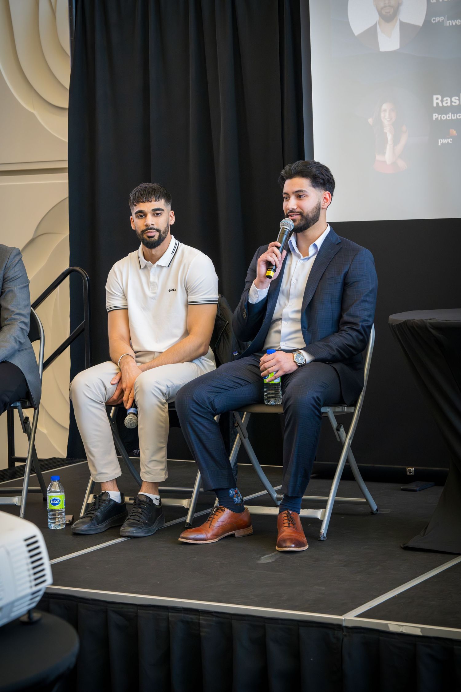 Speakers in mixed formal and casual attire seated on stage during panel event.