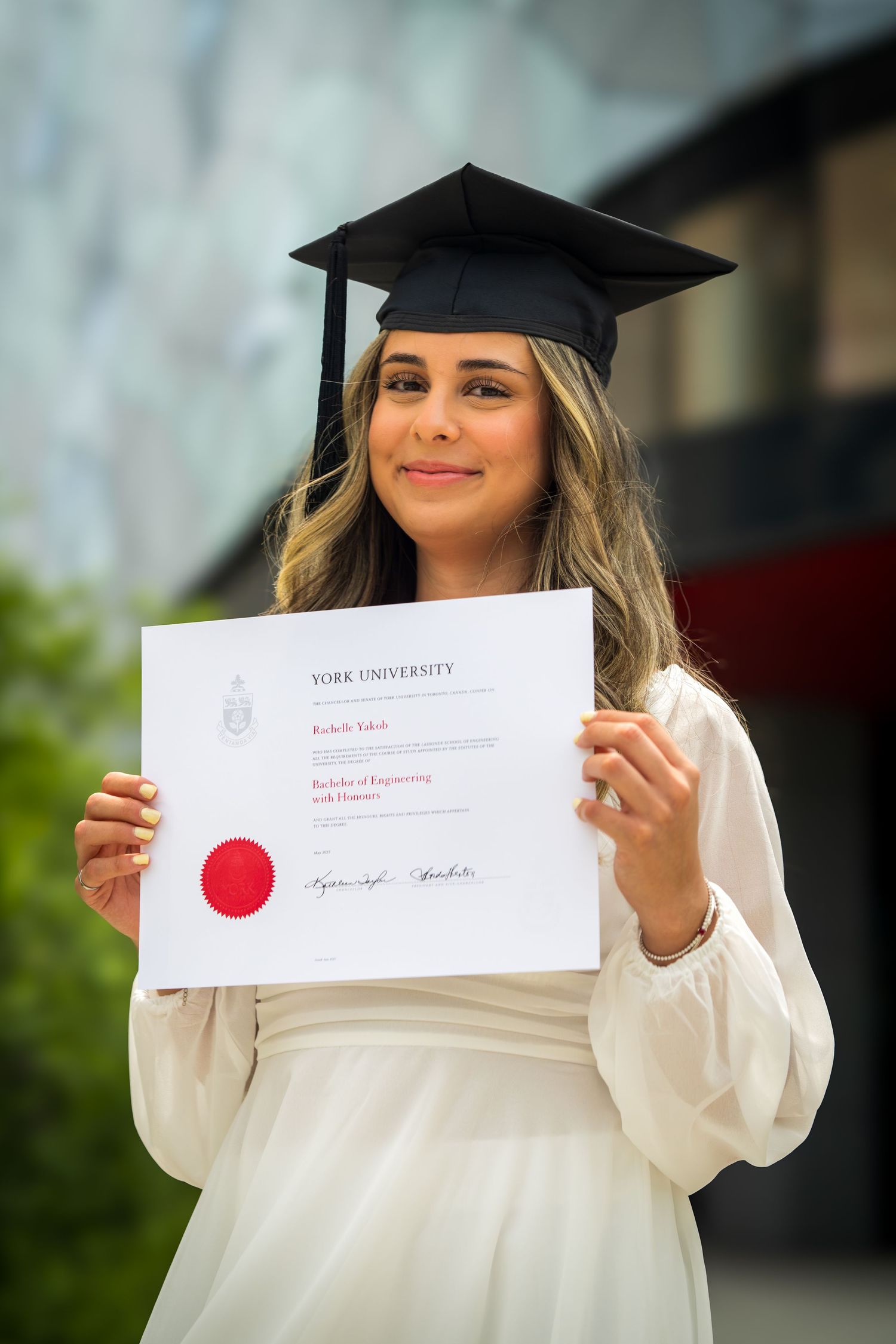 Graduate holds York University diploma while wearing traditional graduation cap.