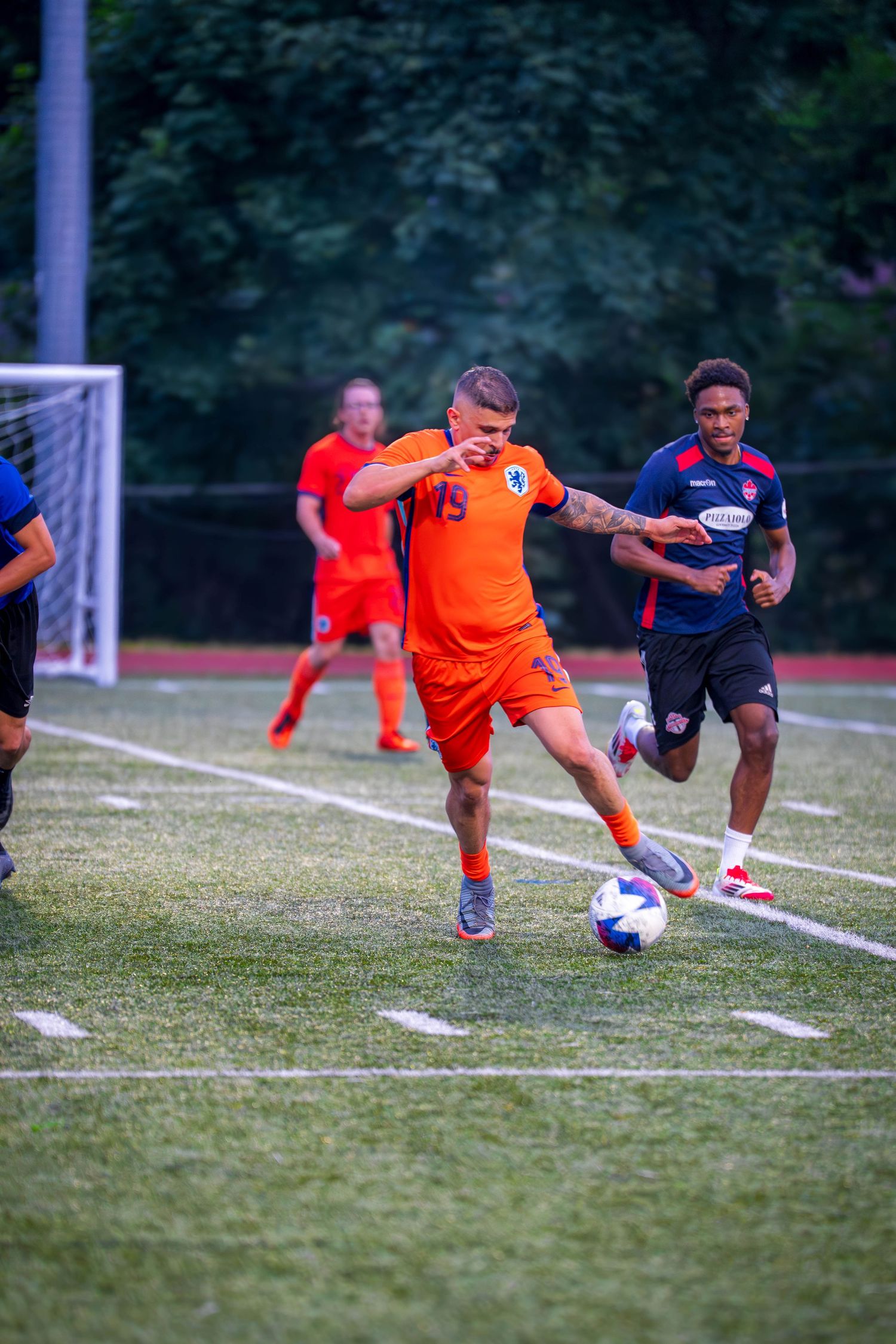 Soccer players dive and stretch for the ball during an intense match moment.