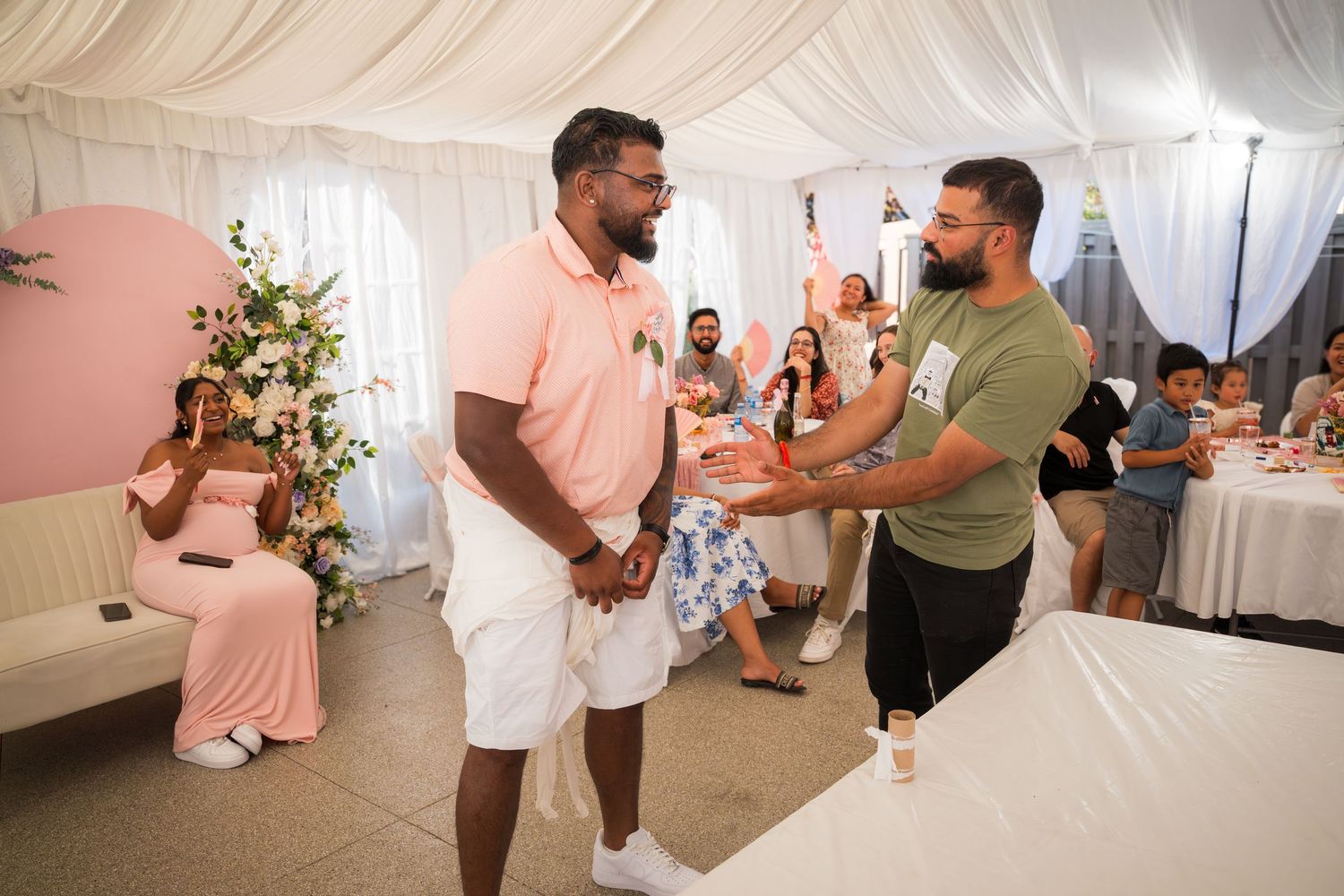 People gathered for a celebration in a tent-draped venue with brick walls.
