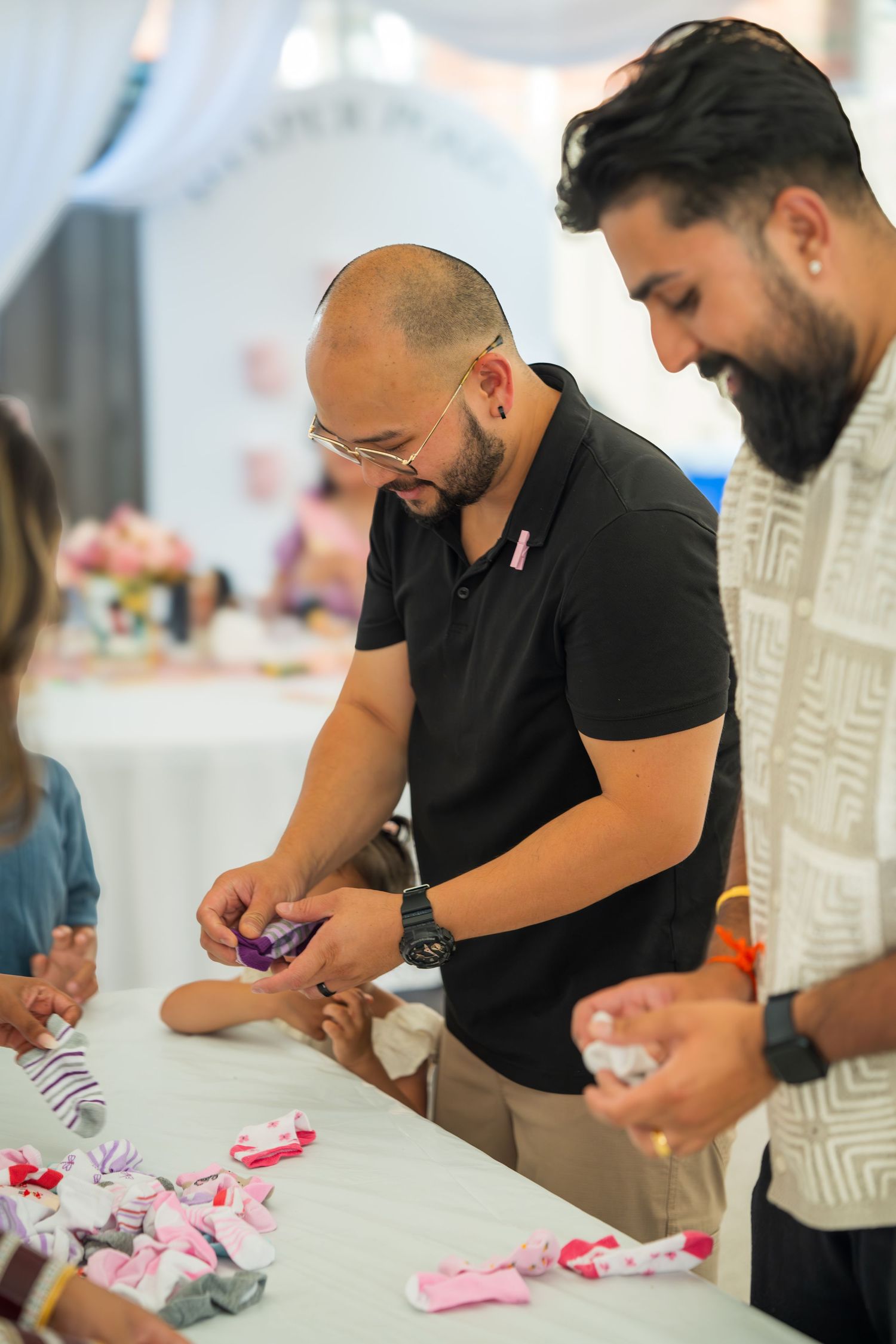 People in black shirts focused on a detailed crafting activity at a white table.