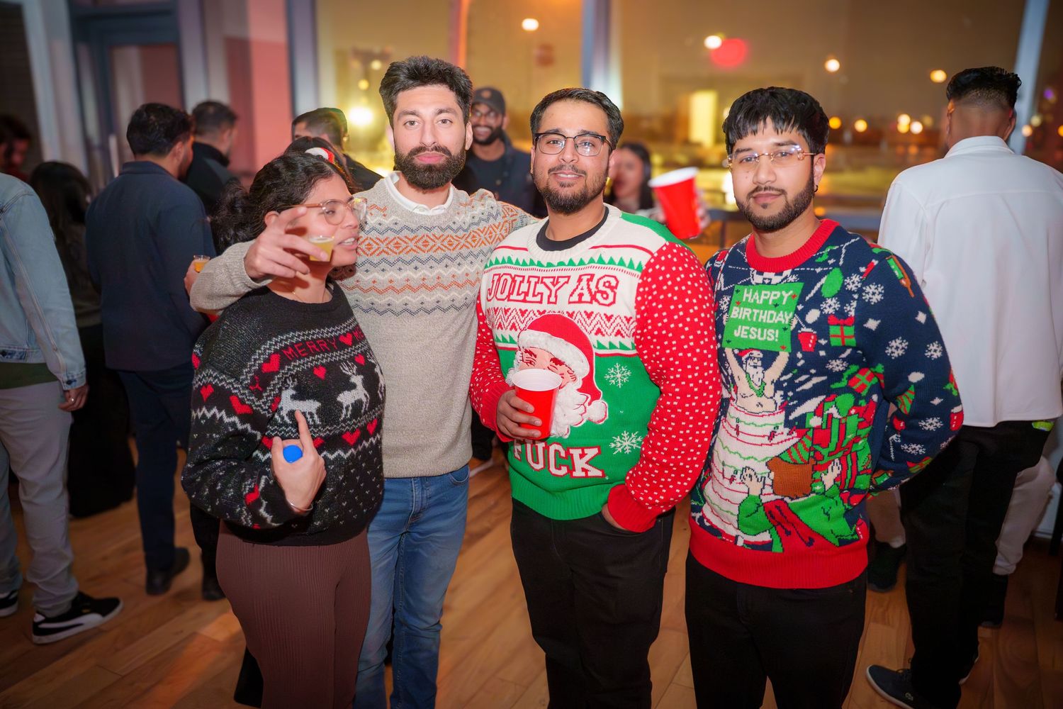 Group wearing festive Christmas sweaters posing together at a holiday celebration.