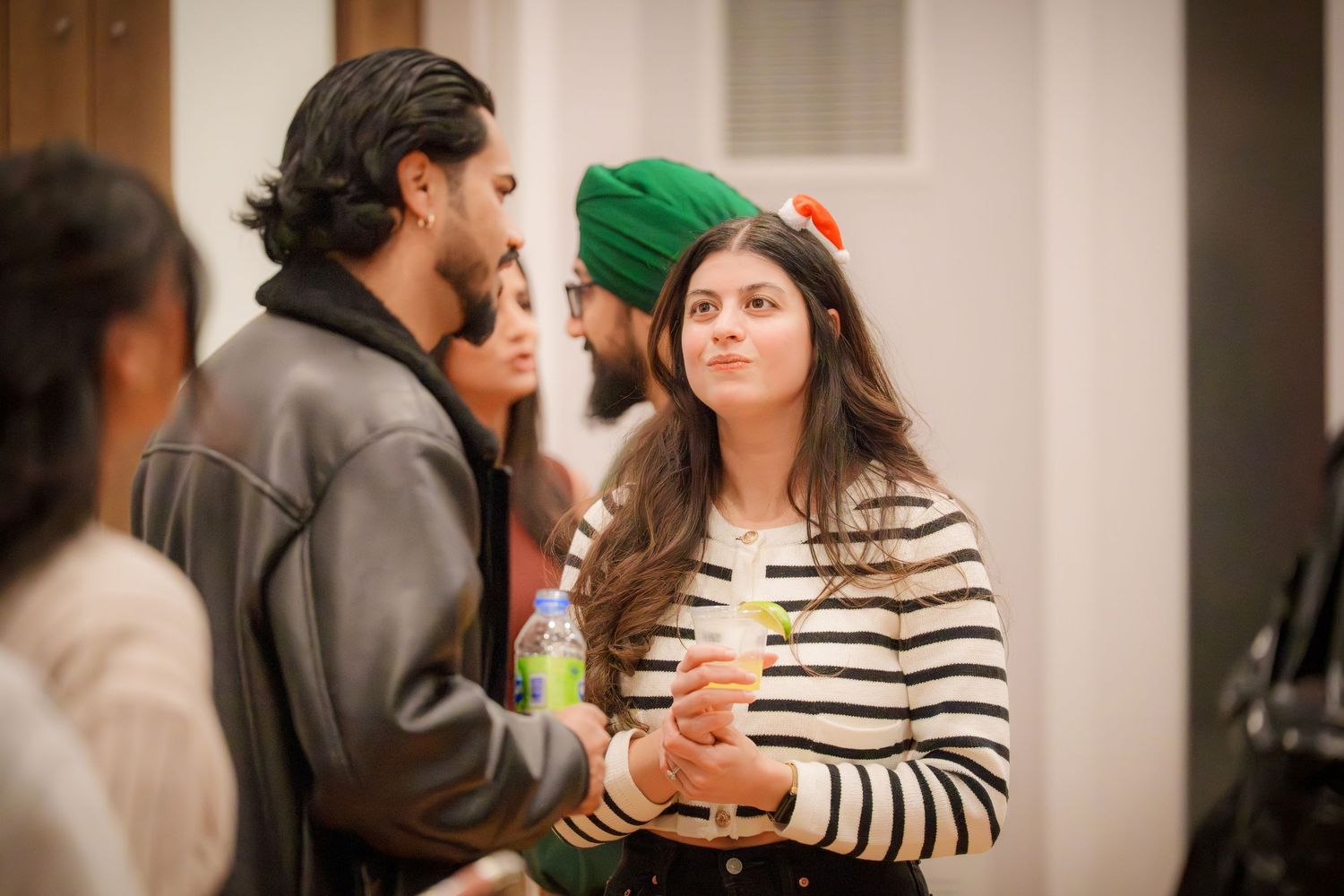 People engaged in conversation at a casual indoor gathering with striped walls.