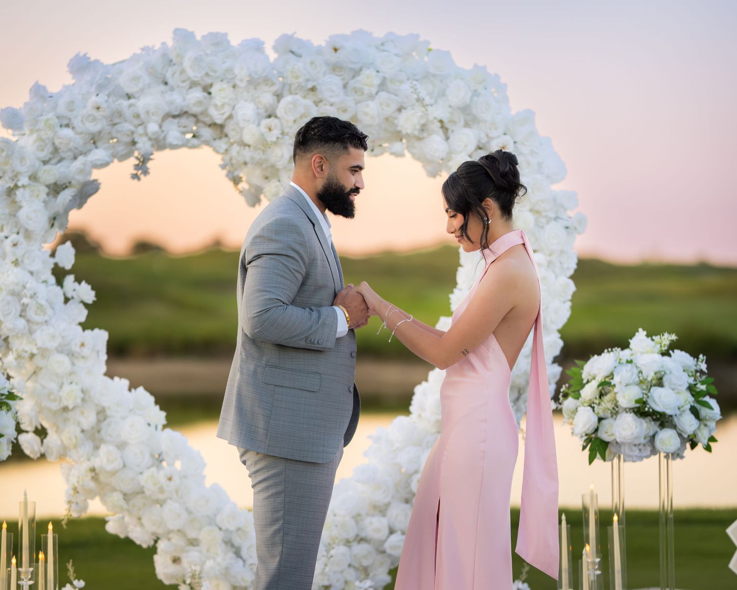 An intimate moment captured under a white flower arch with candlelit decor.