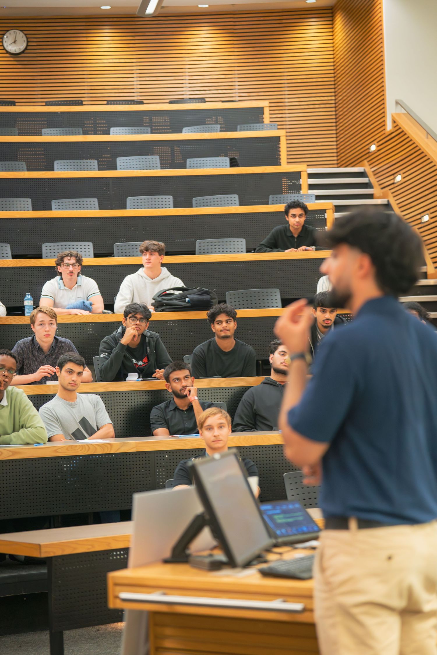 Wide view of lecture hall showing presenter and engaged audience members.