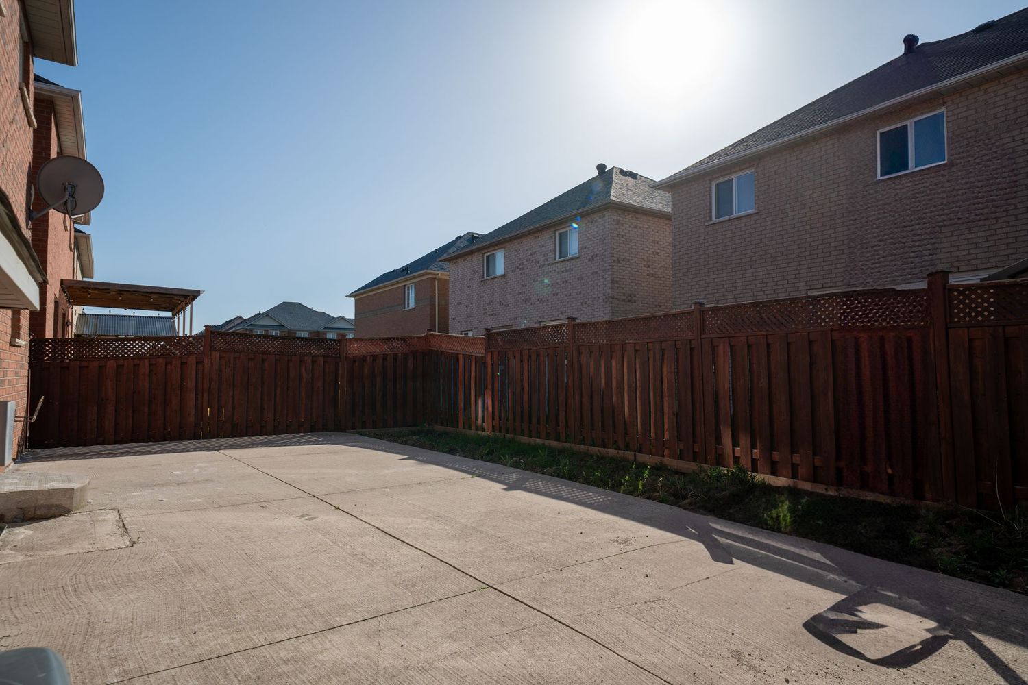 Concrete patio surrounded by wooden privacy fence with suburban houses visible in the background.