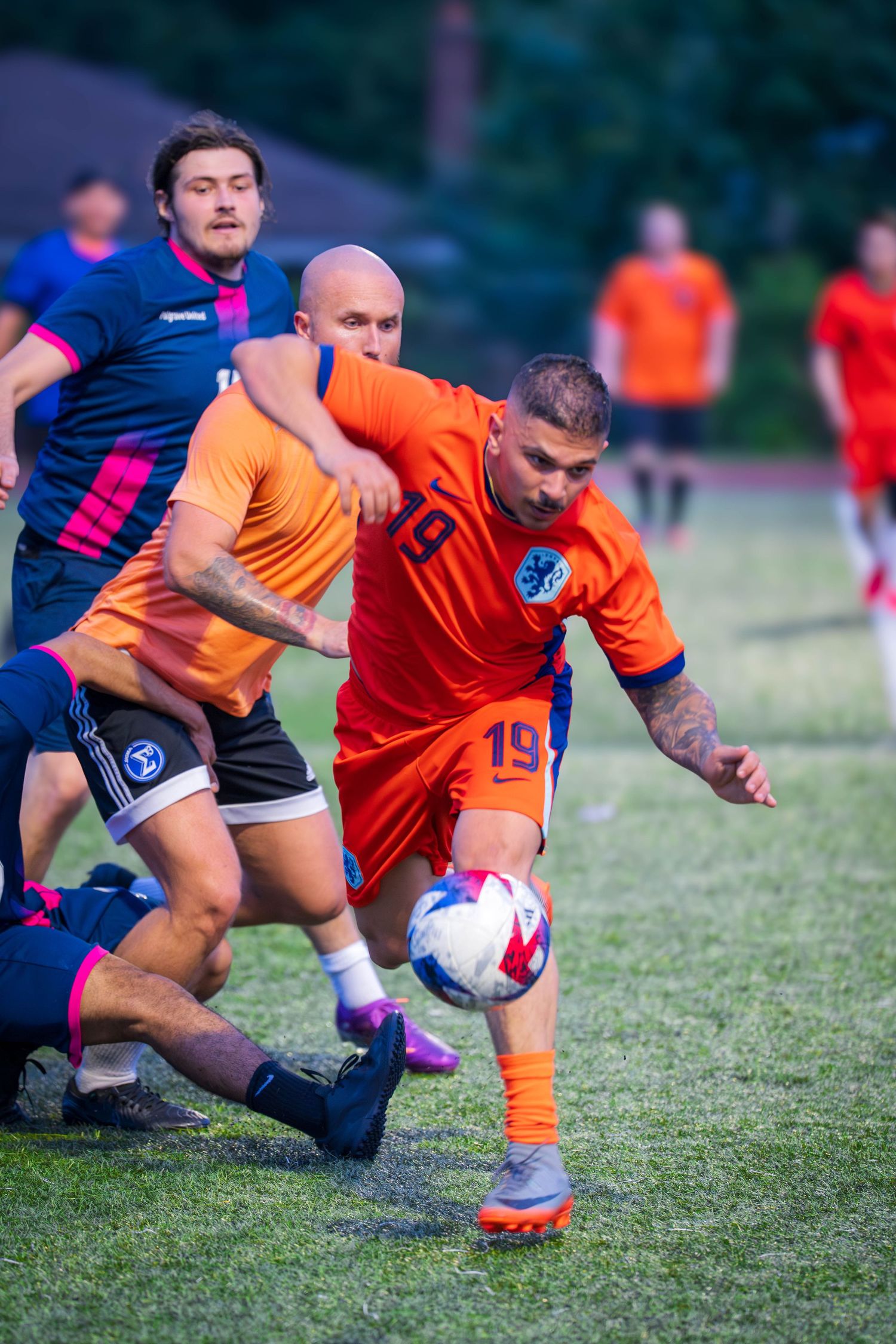 Players compete for possession of soccer ball during competitive match on grass field.