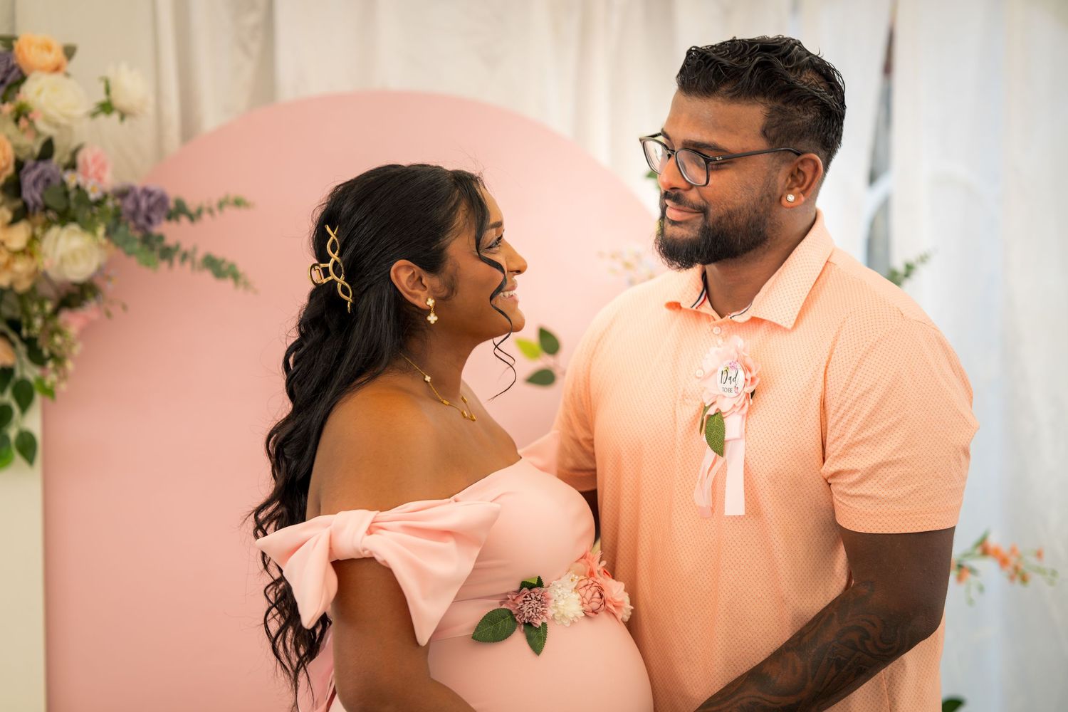 A couple sharing joyful moments at a celebration with soft pink and white decor.